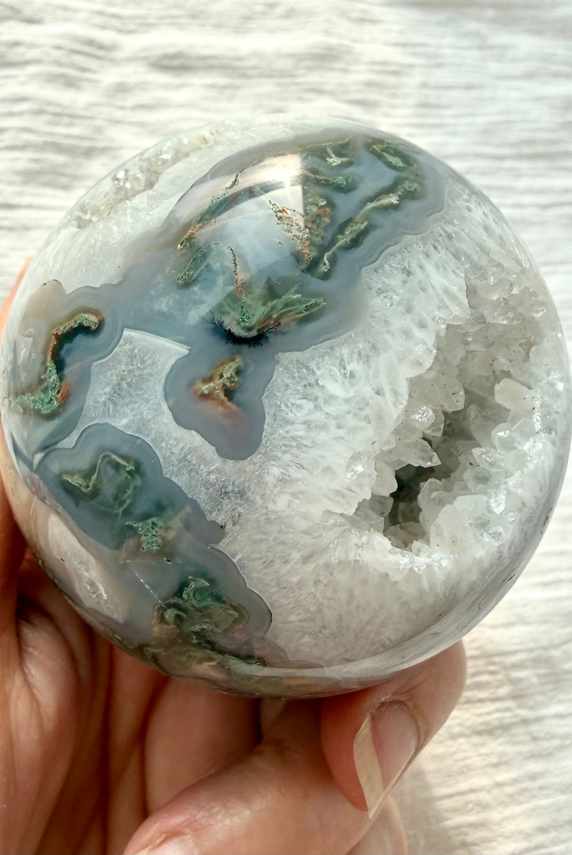Moss Agate geode crystal ball showing sparkling Quartz cave surrounded by white and gray chalcedony banding
