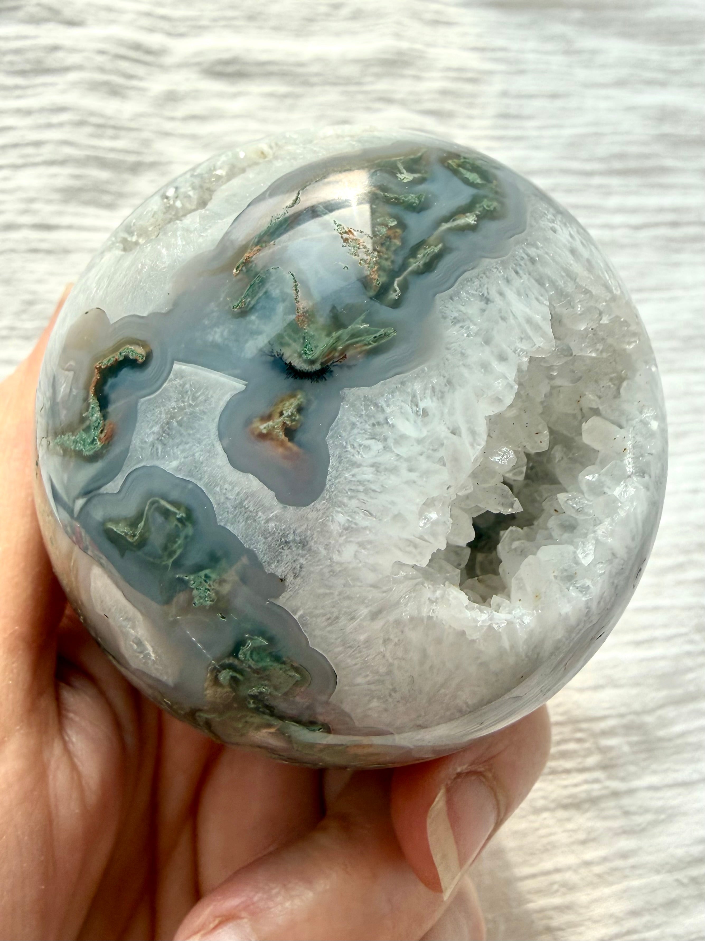 Moss Agate geode crystal ball showing sparkling Quartz cave surrounded by white and gray chalcedony banding