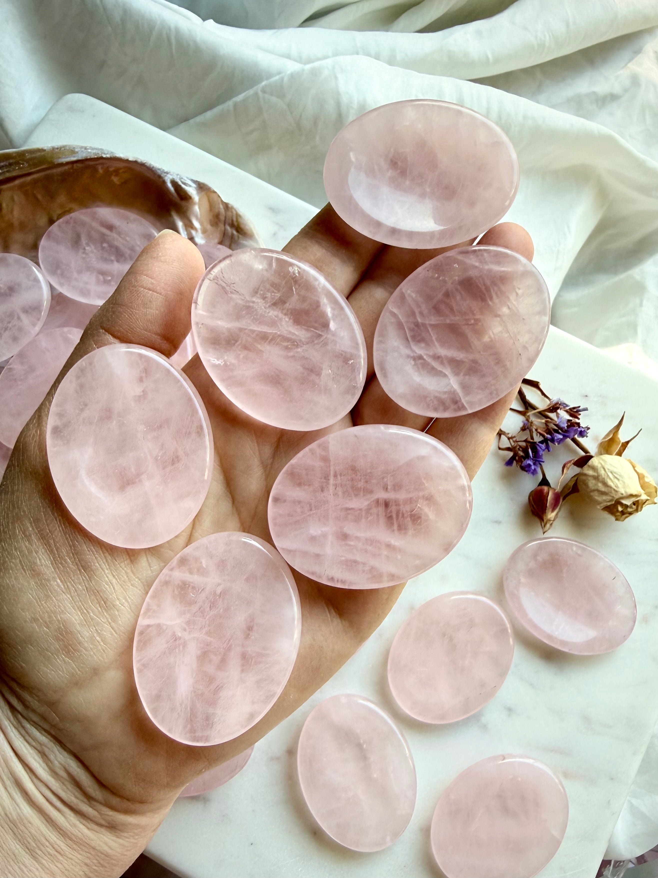 multiple rose quartz worry stones shown on hand for size scale, calming crystals for meditation