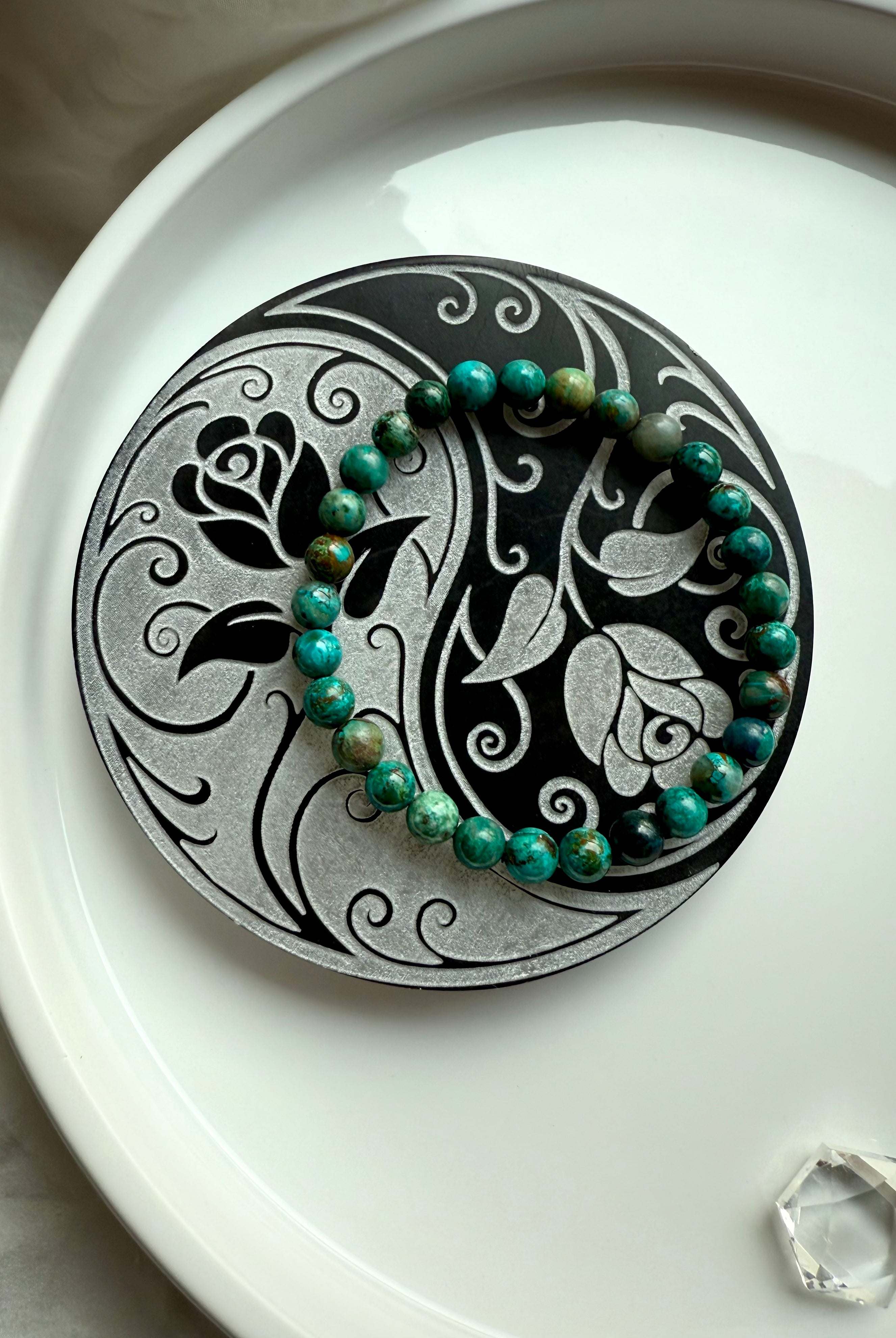 Gemstone bracelet resting on yin yang rose selenite charging plate for crystal cleansing and recharging