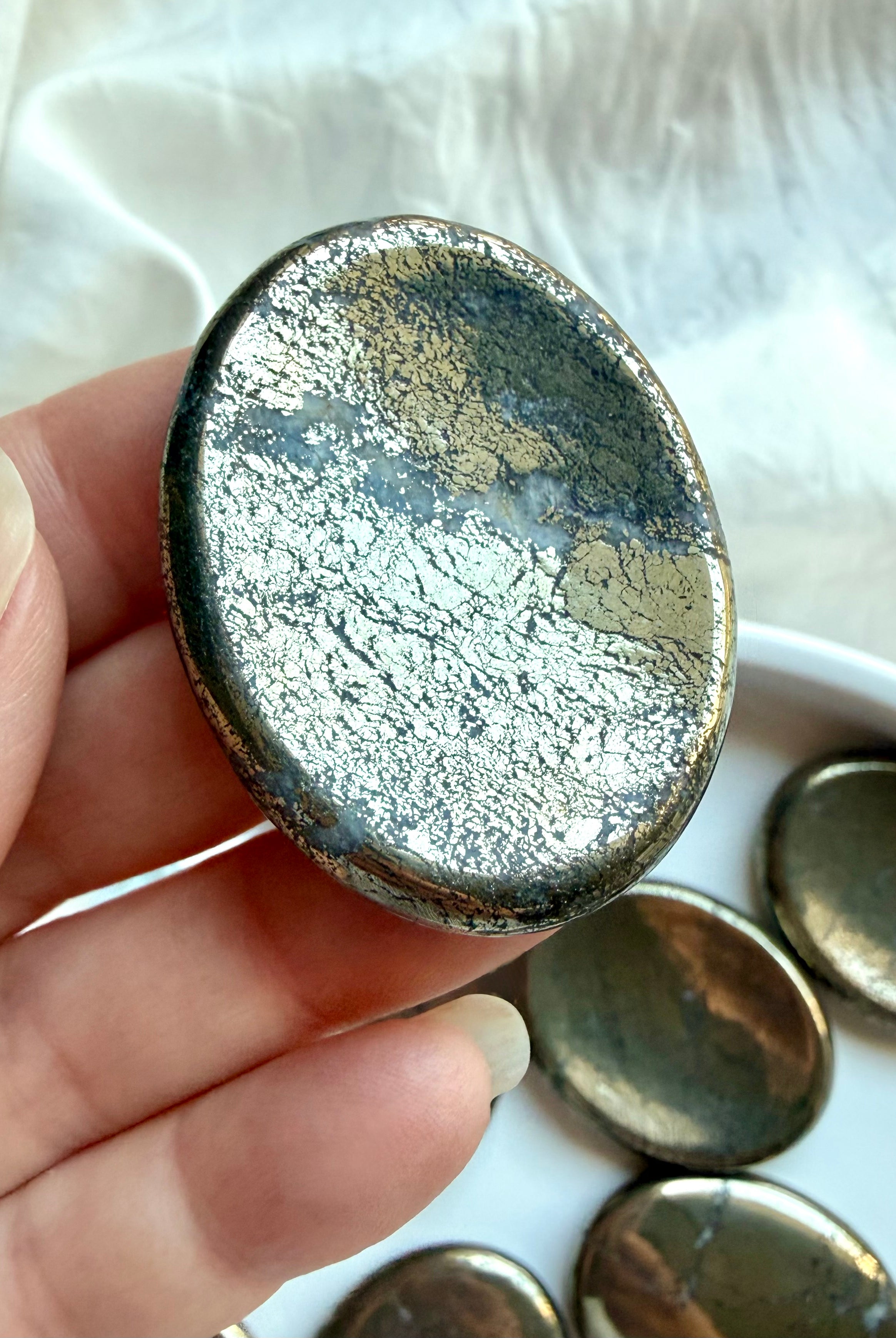 Pyrite worry stone close-up showing reflective gold surface, crystalline texture and natural patina
