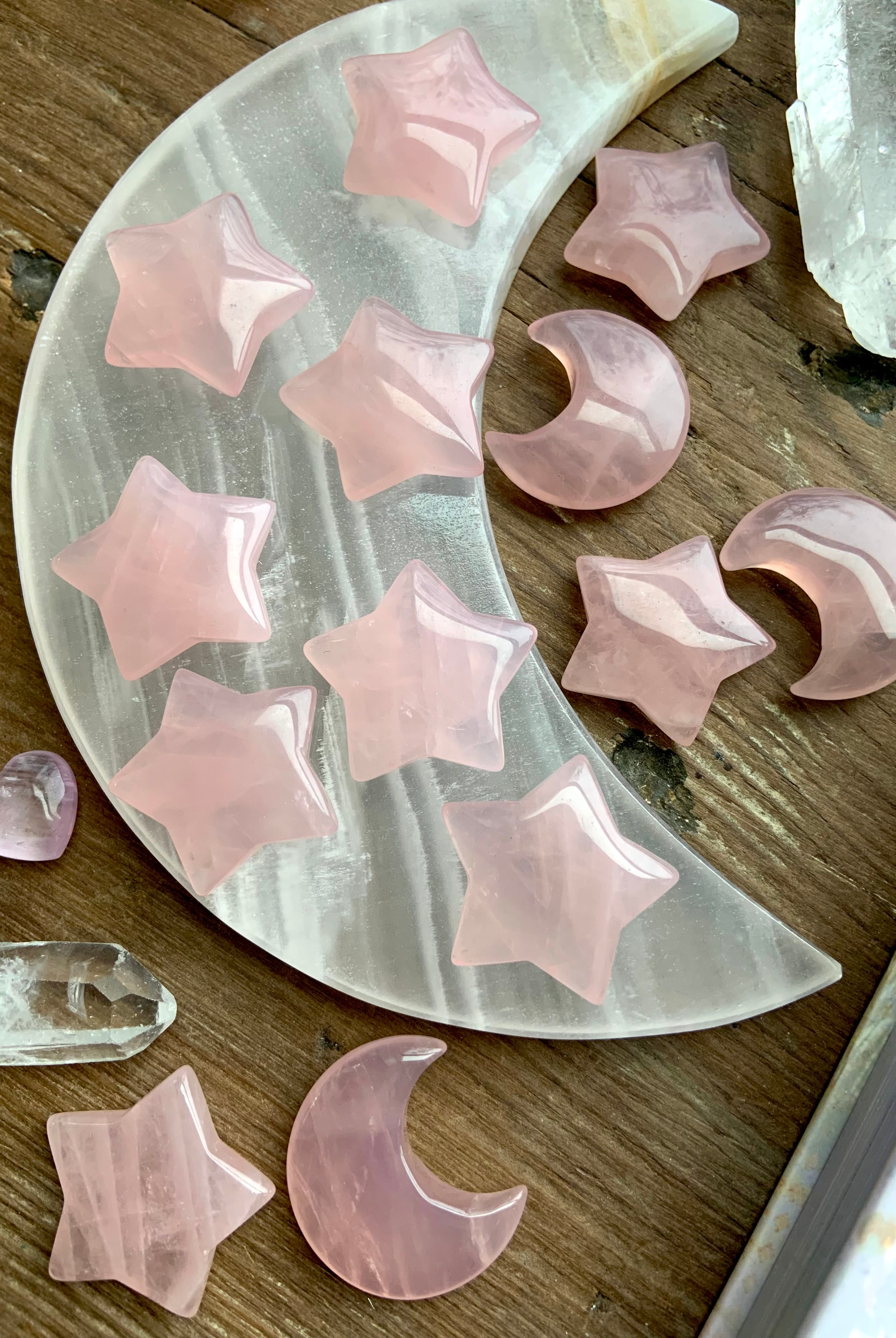 Angled view of rose quartz crystal moons and stars on a white onyx moon plate with quartz crystals