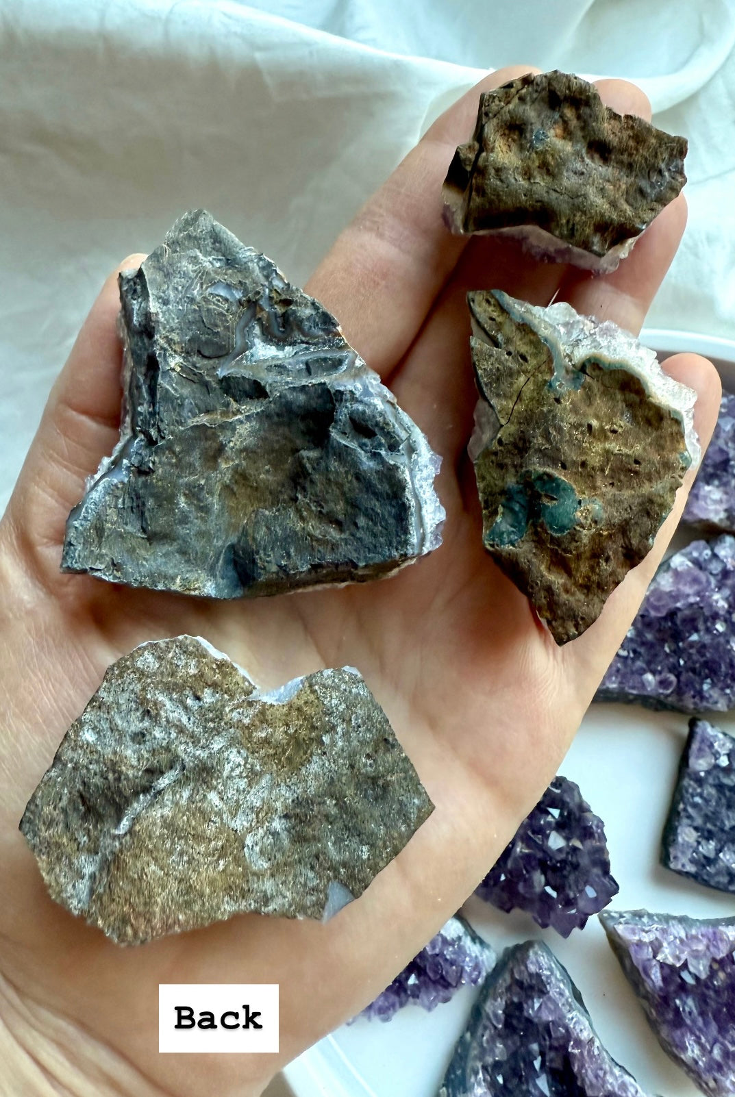 Back view of four amethyst crystal clusters with natural geode matrix crust