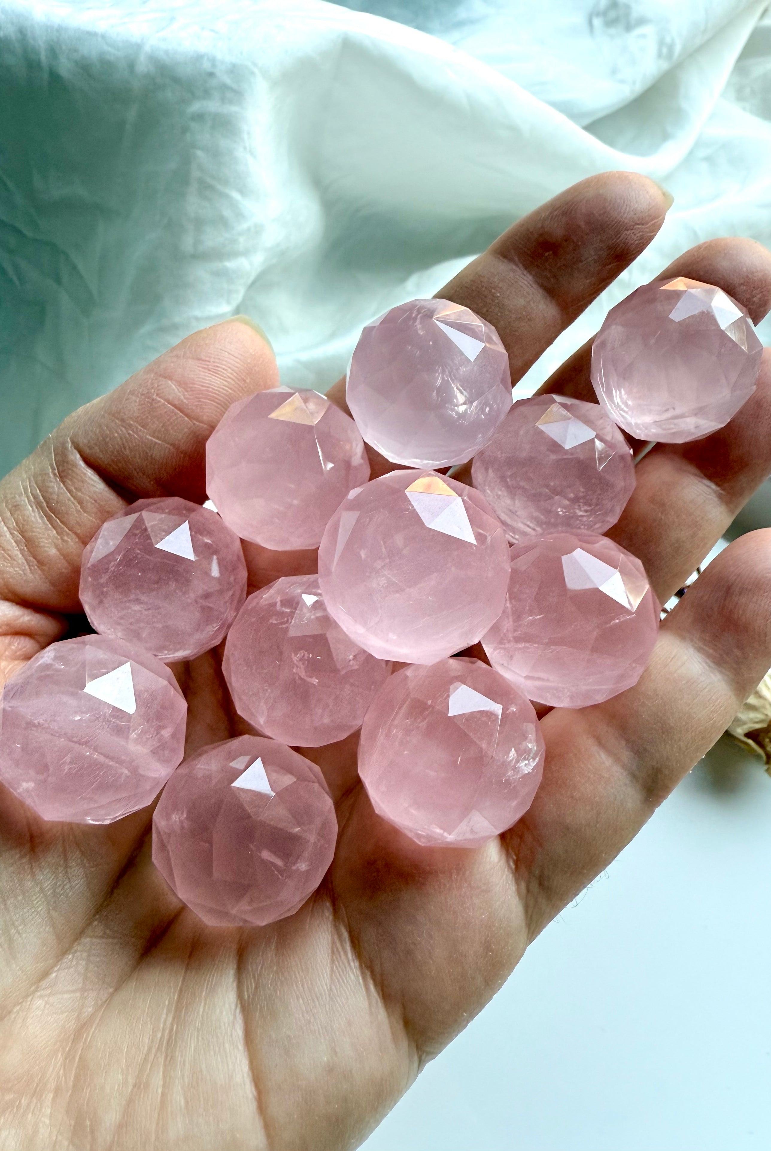 Hand holding high quality rose quartz crystal spheres. Heart chakra healing stones for love.