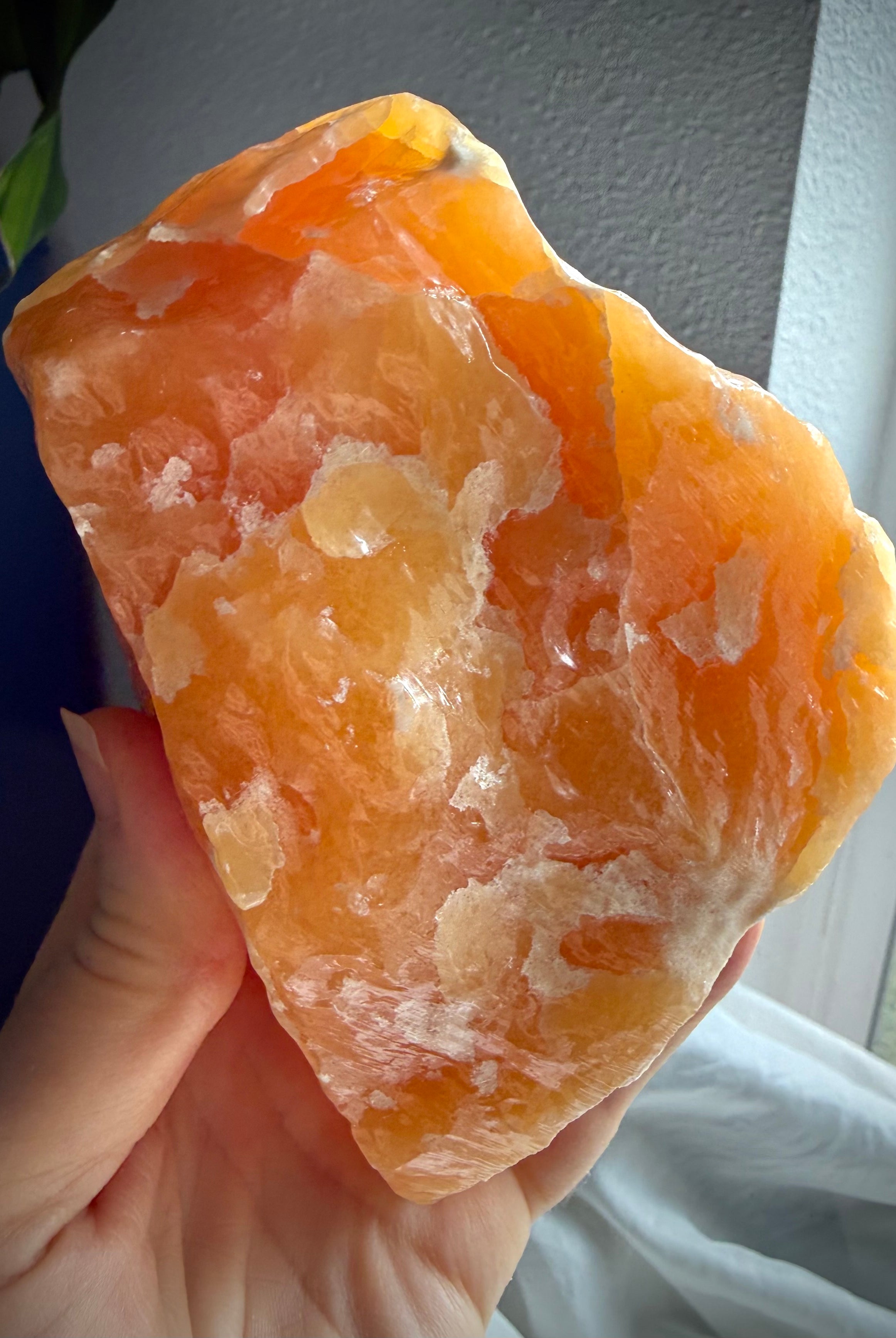 Handheld Orange Calcite crystal specimen with vibrant orange tones and substantial display presence