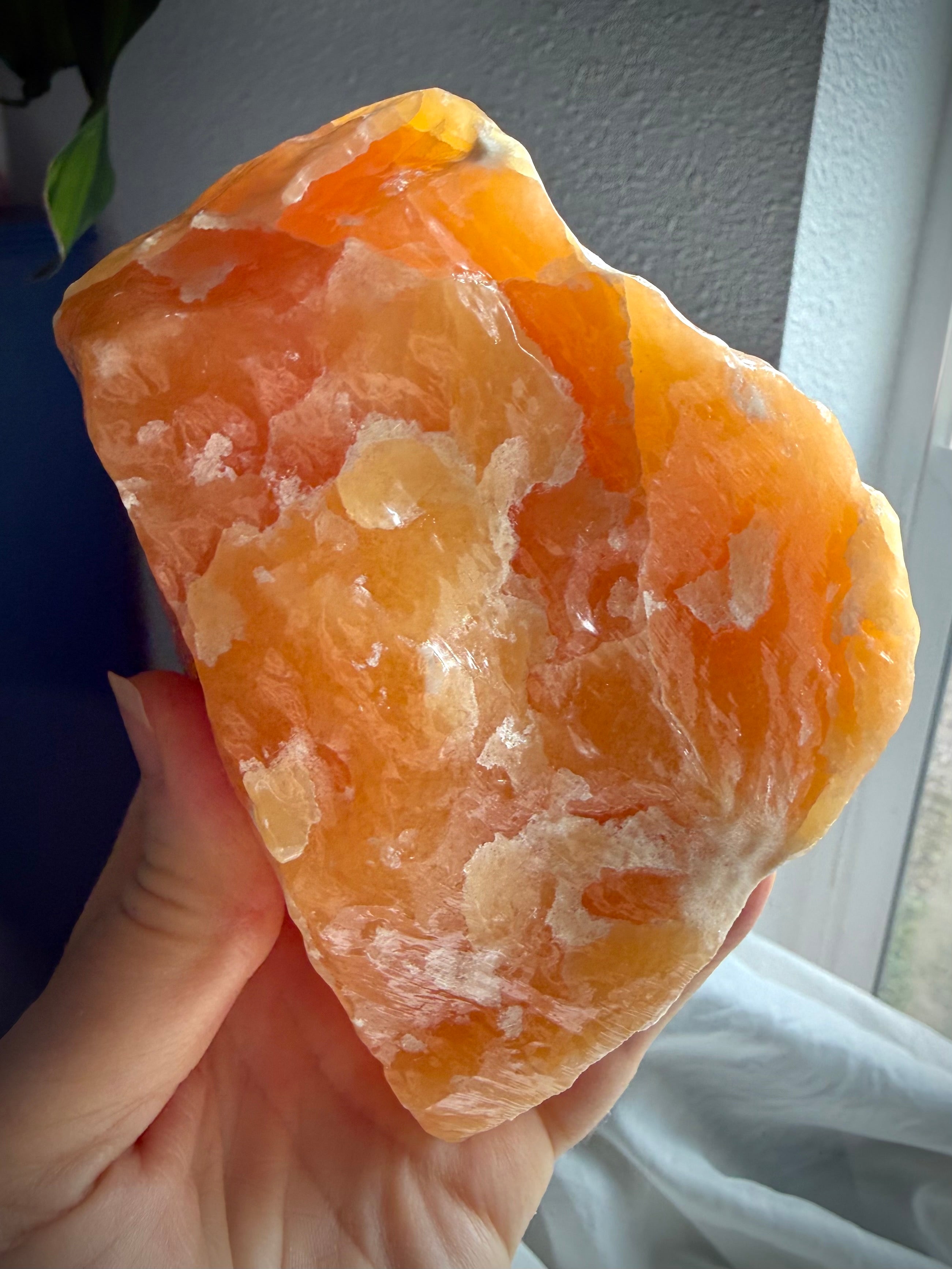 Handheld Orange Calcite crystal specimen with vibrant orange tones and substantial display presence