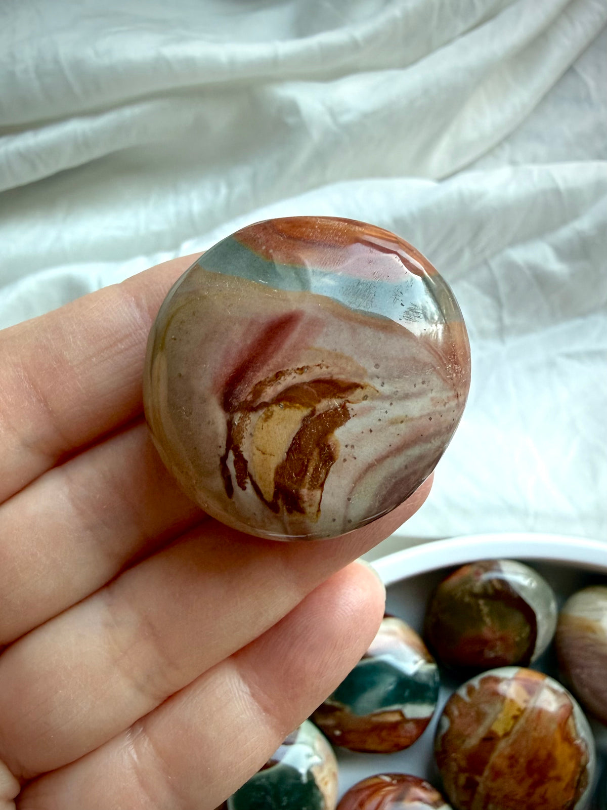 Polished Polychrome Jasper pocket stone with swirling terracotta, tan, and sage green bands in a rounded mini palm shape