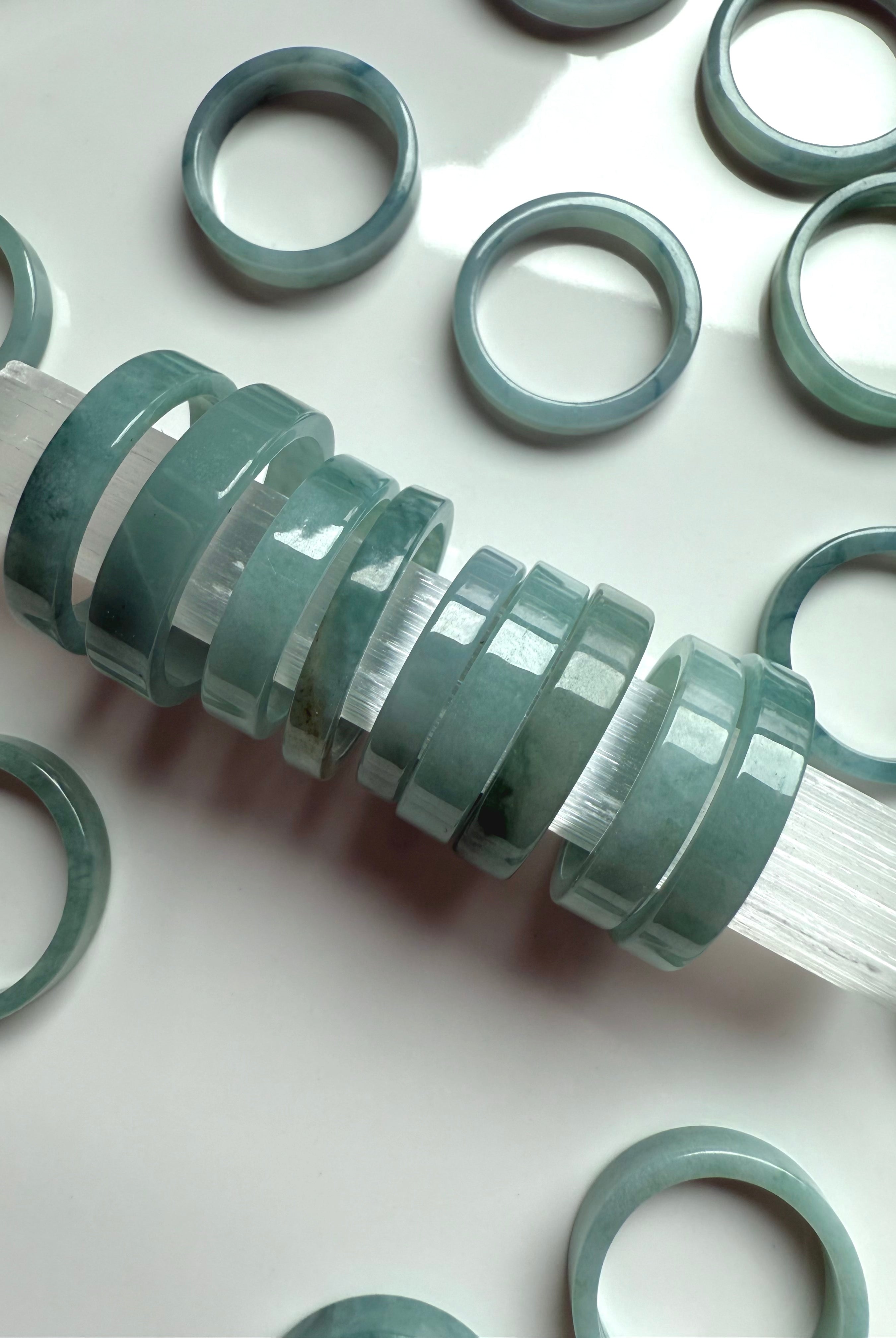 Blue Water Jade crystal rings lined up on a selenite wand for cleansing and presentation