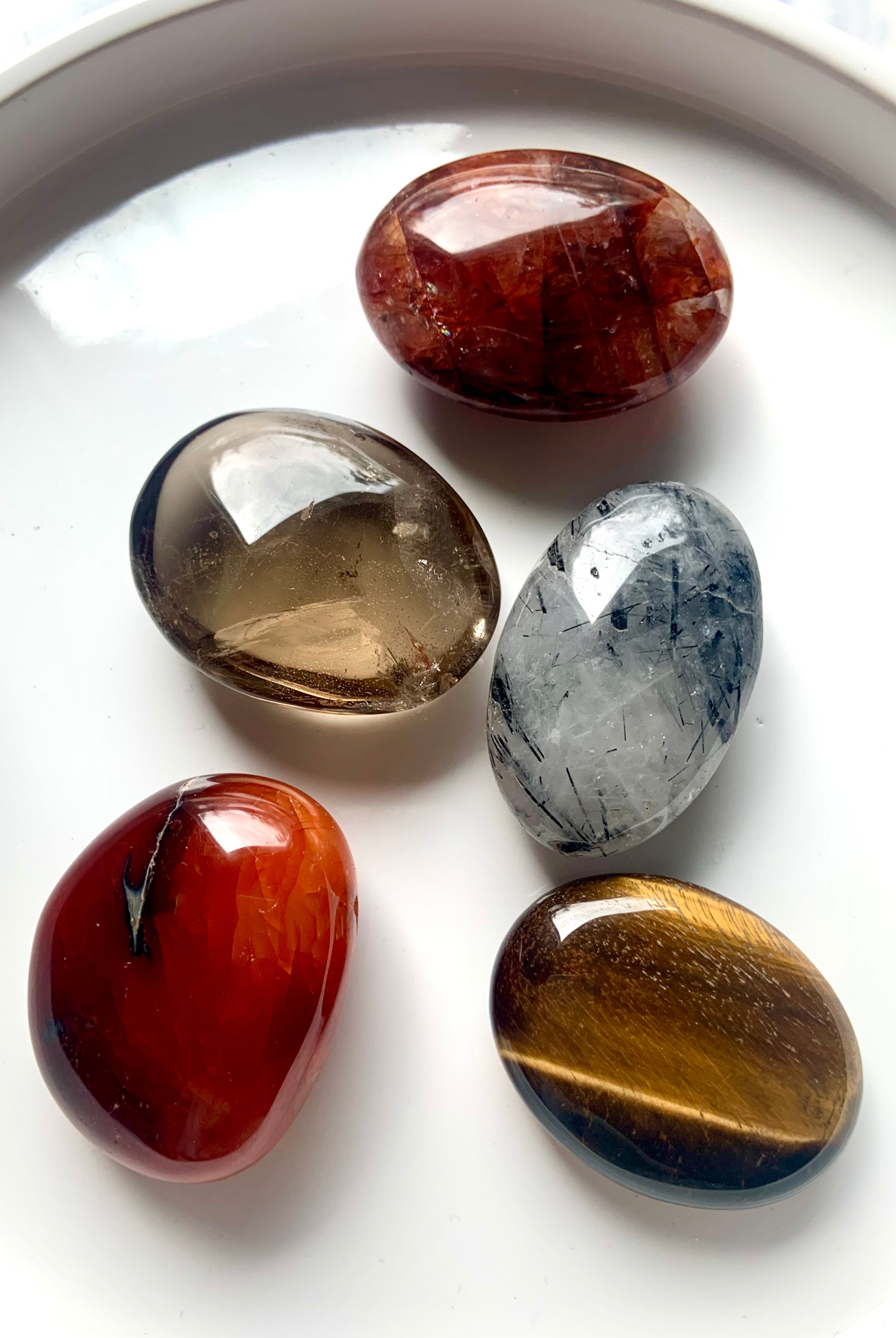 Root, Sacral + Solar Plexus Chakra palm stone set on white plate — high-quality polished crystals for grounding, creativity & personal power.