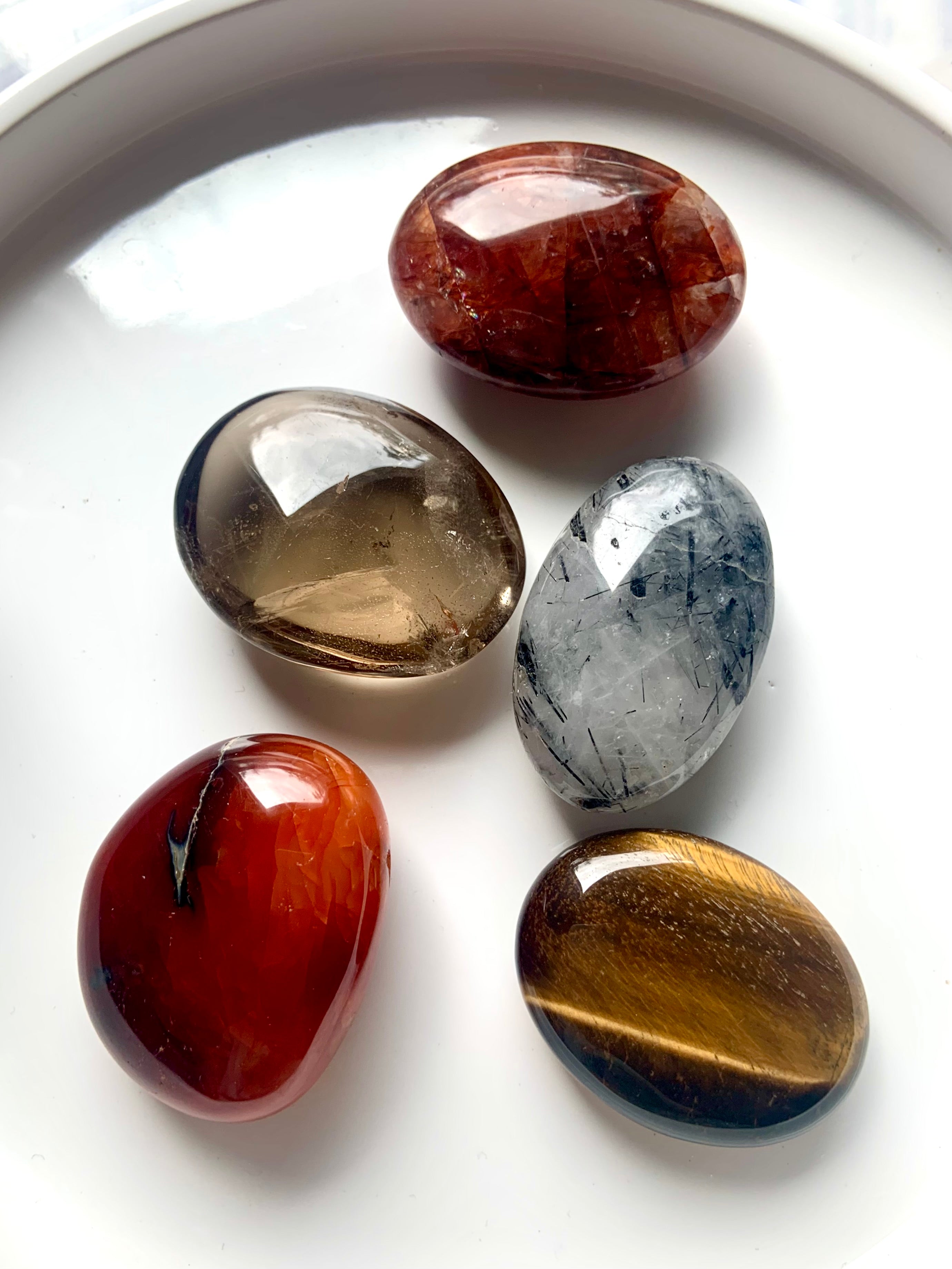 Root, Sacral + Solar Plexus Chakra palm stone set on white plate — high-quality polished crystals for grounding, creativity & personal power.