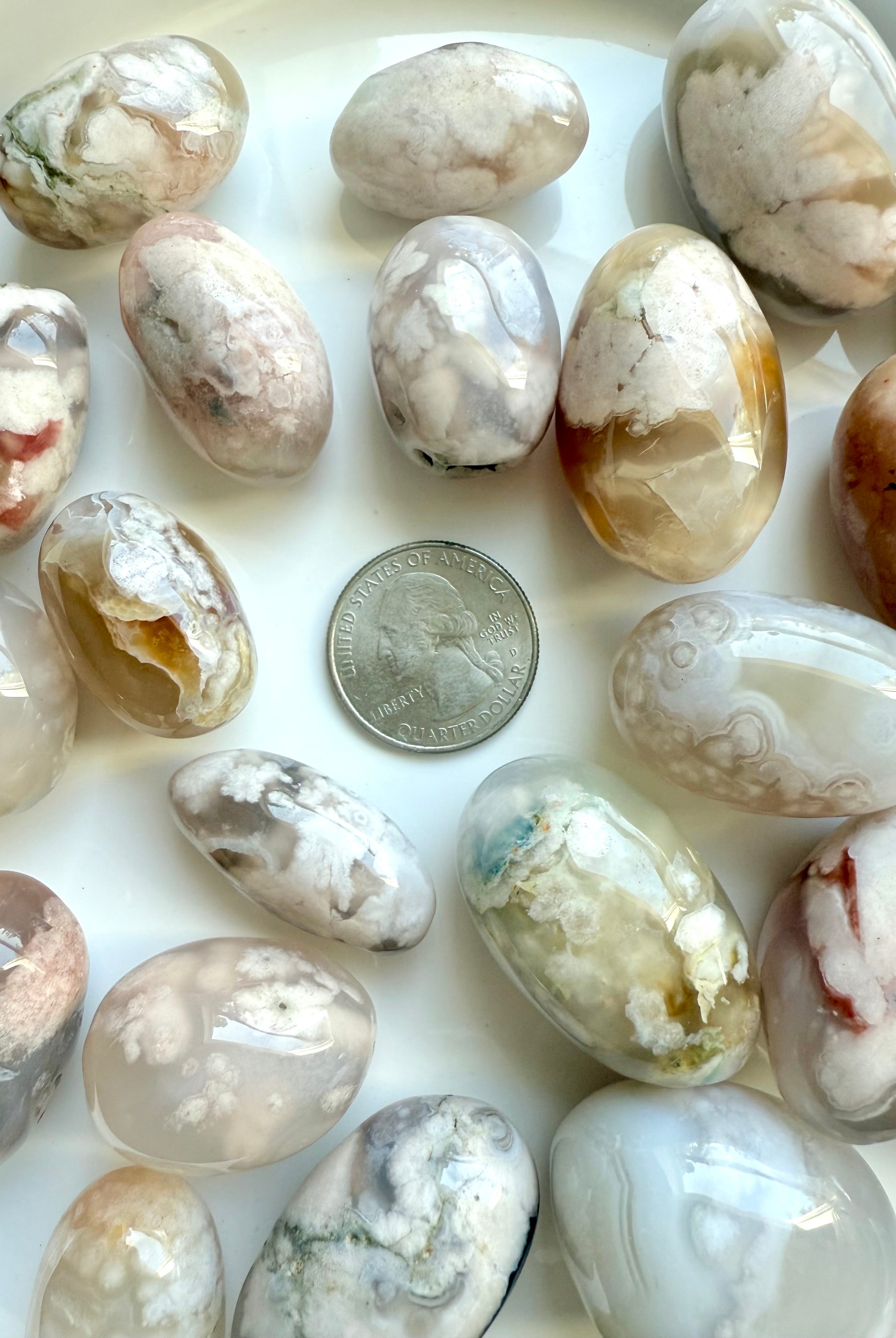 High quality Flower Agate tumbled stones with pastel color patterns shown with a quarter for scale