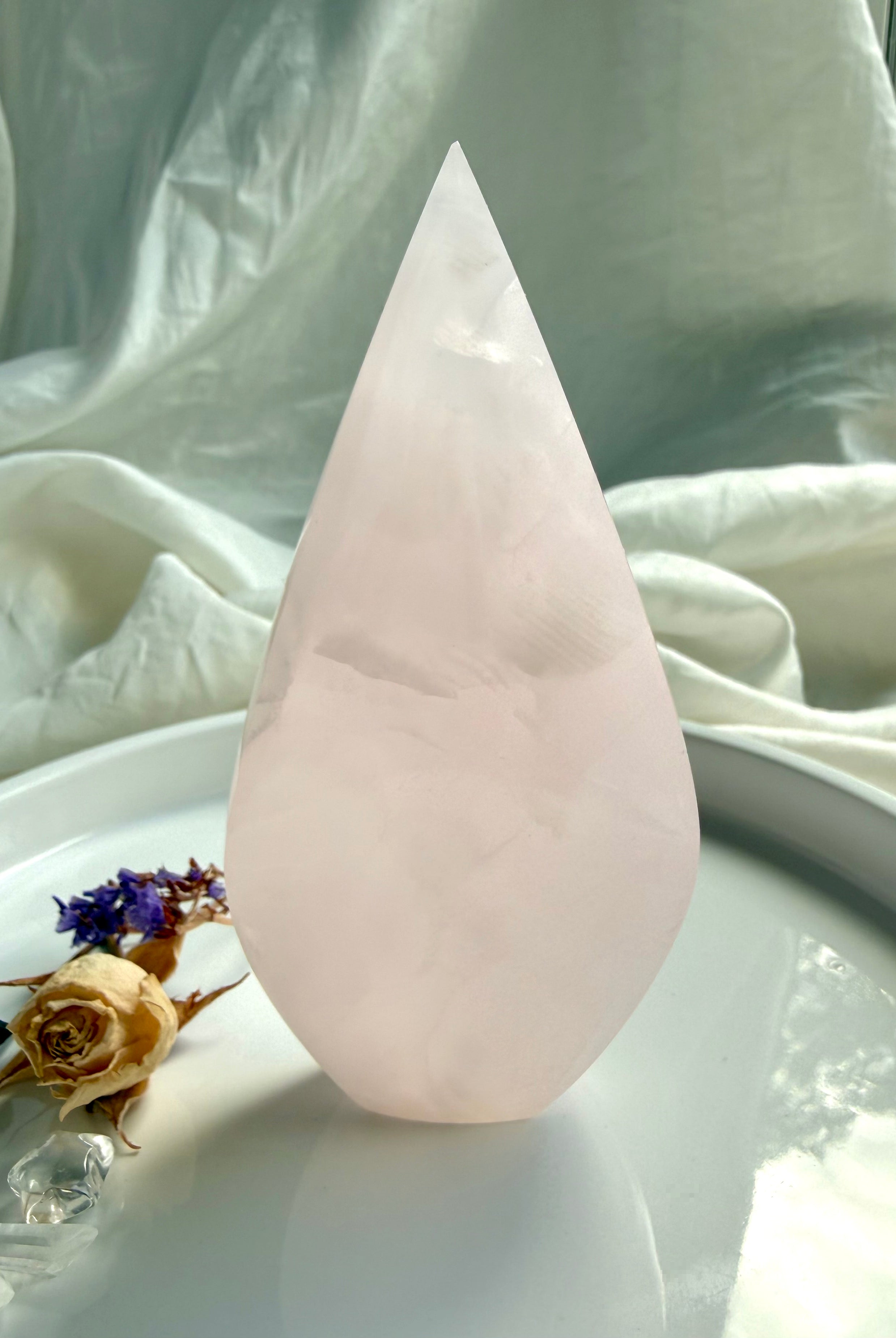 Mangano Calcite flame crystal in hand for size reference with luminous pink color and subtle internal patterning