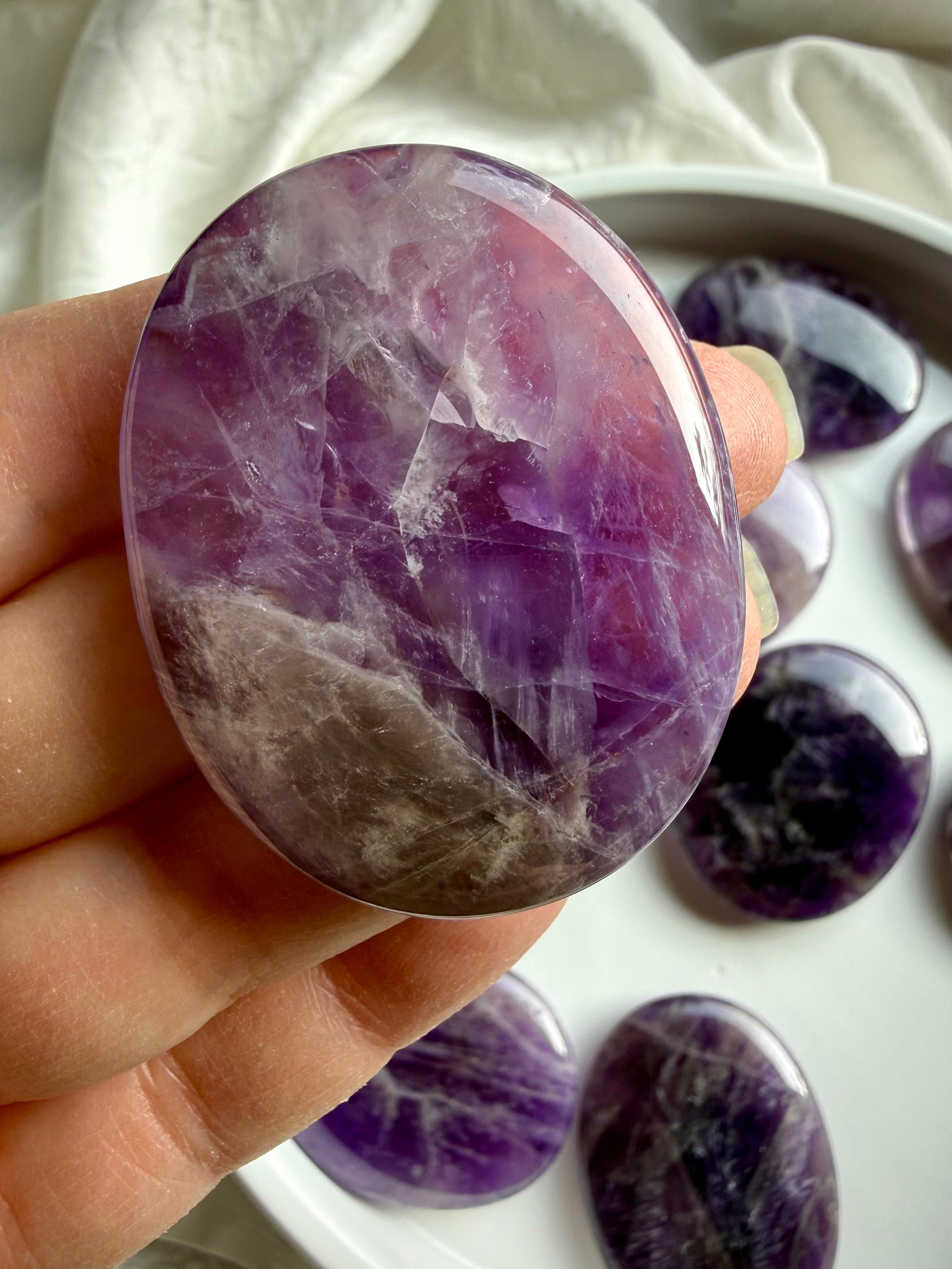 Dream amethyst flat palm stone held in hand, smooth calming pocket crystal for stress relief, meditation, and grounding energy