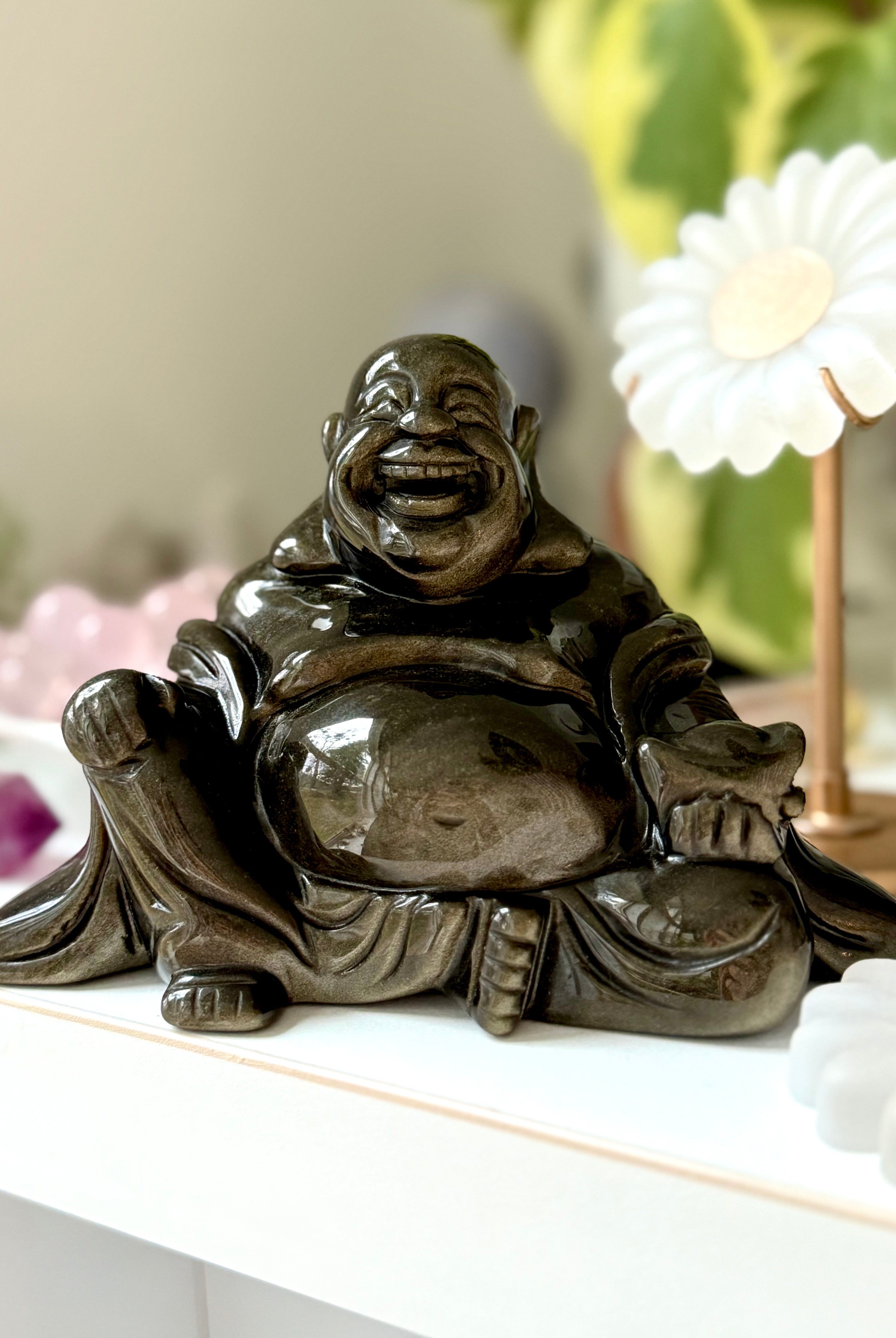 Golden Sheen Obsidian Buddha statue on crystal altar with flower decor – crystal carving for protection, abundance, and solar plexus healing