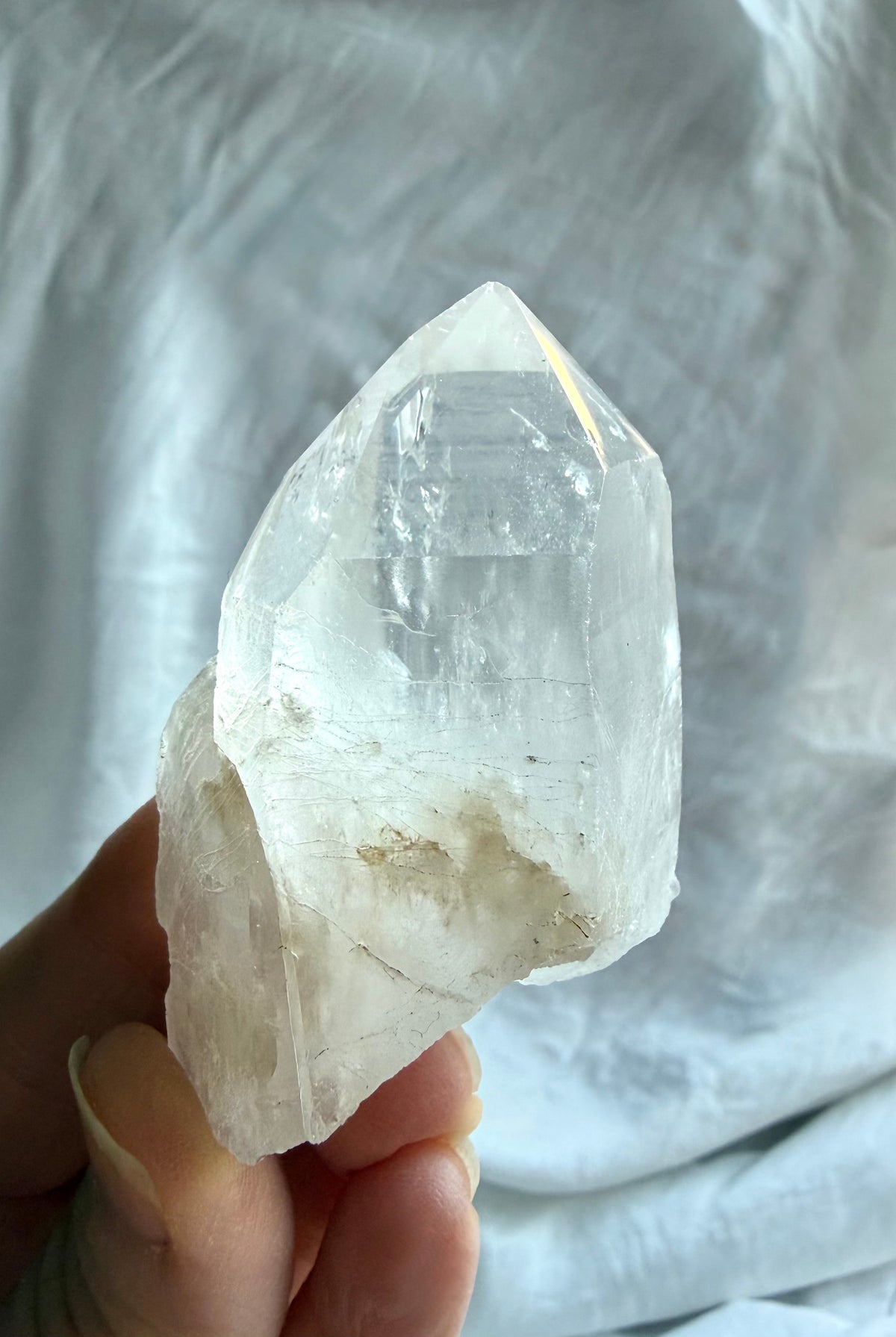 Natural Lemurian Quartz crystal point held in hand with rough matrix, cloudy inclusions, and distinctive growth markings