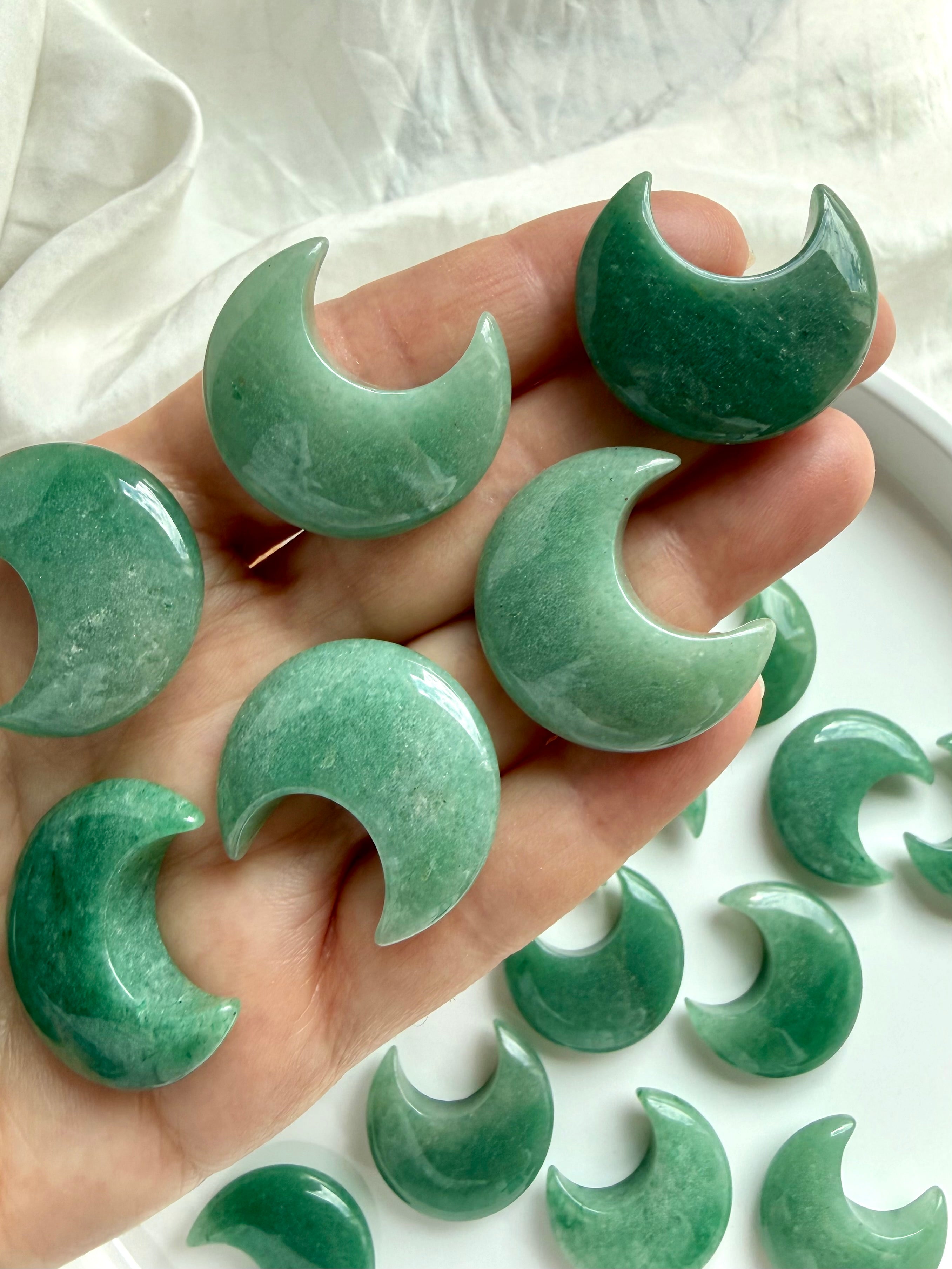 Closeup of Green Aventurine crescent moons shown on hand for scale, soothing crystals for love & abundance