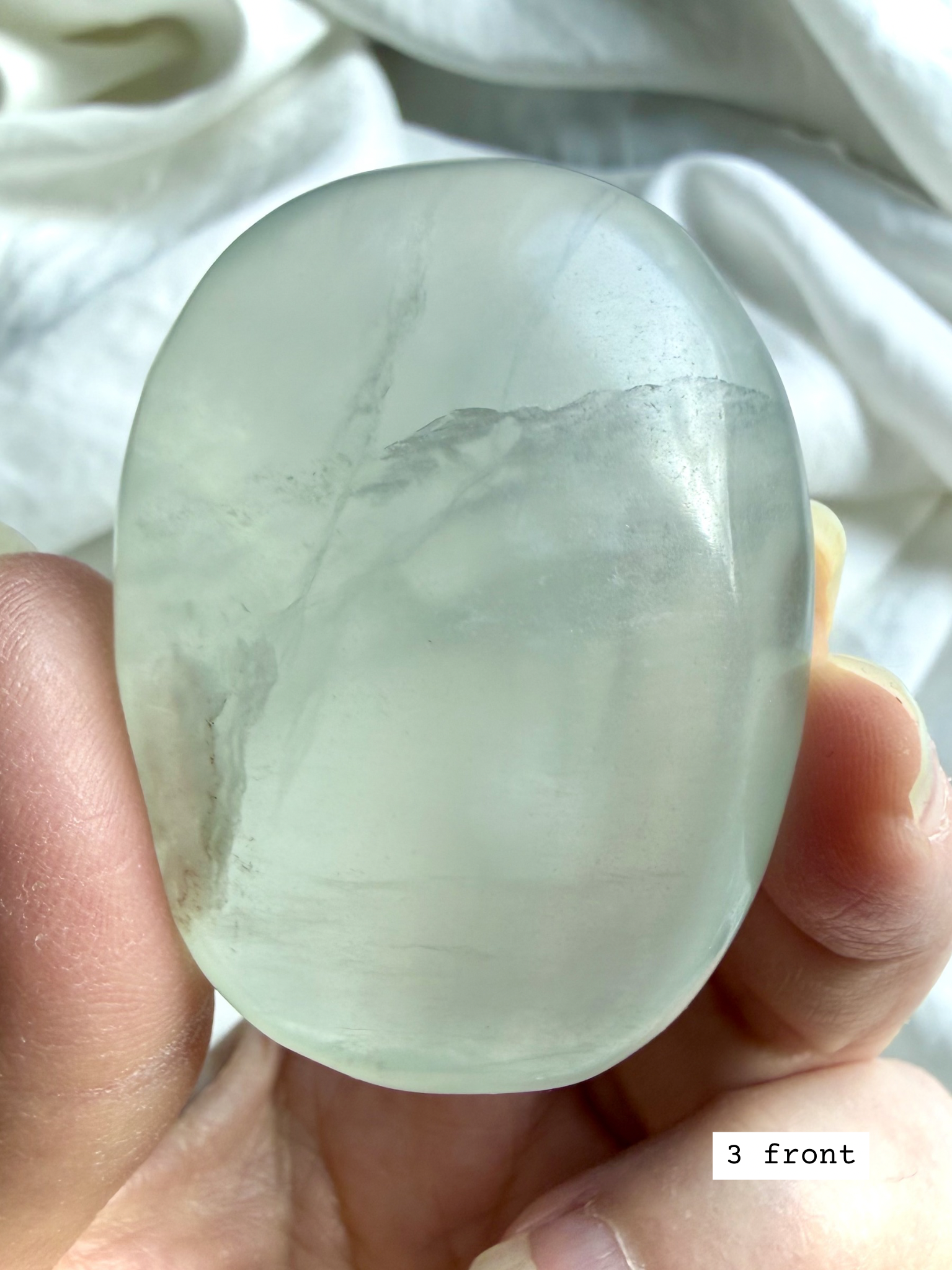 green yttrium fluorite palm stone #3 front view with organic oval shape and translucent glow