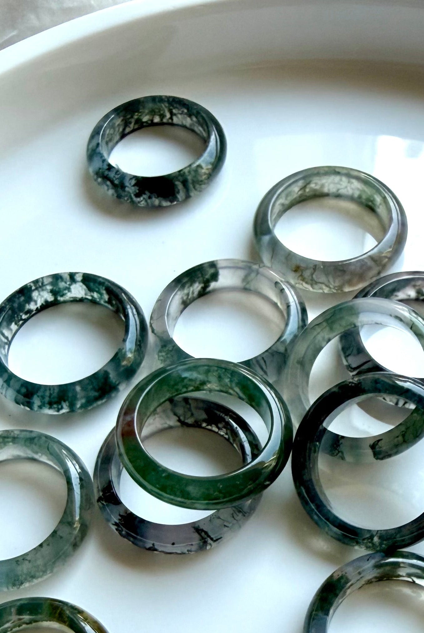 moss agate band rings with translucent green dendritic patterns on marble, crystal rings for grounding growth and heart chakra healing