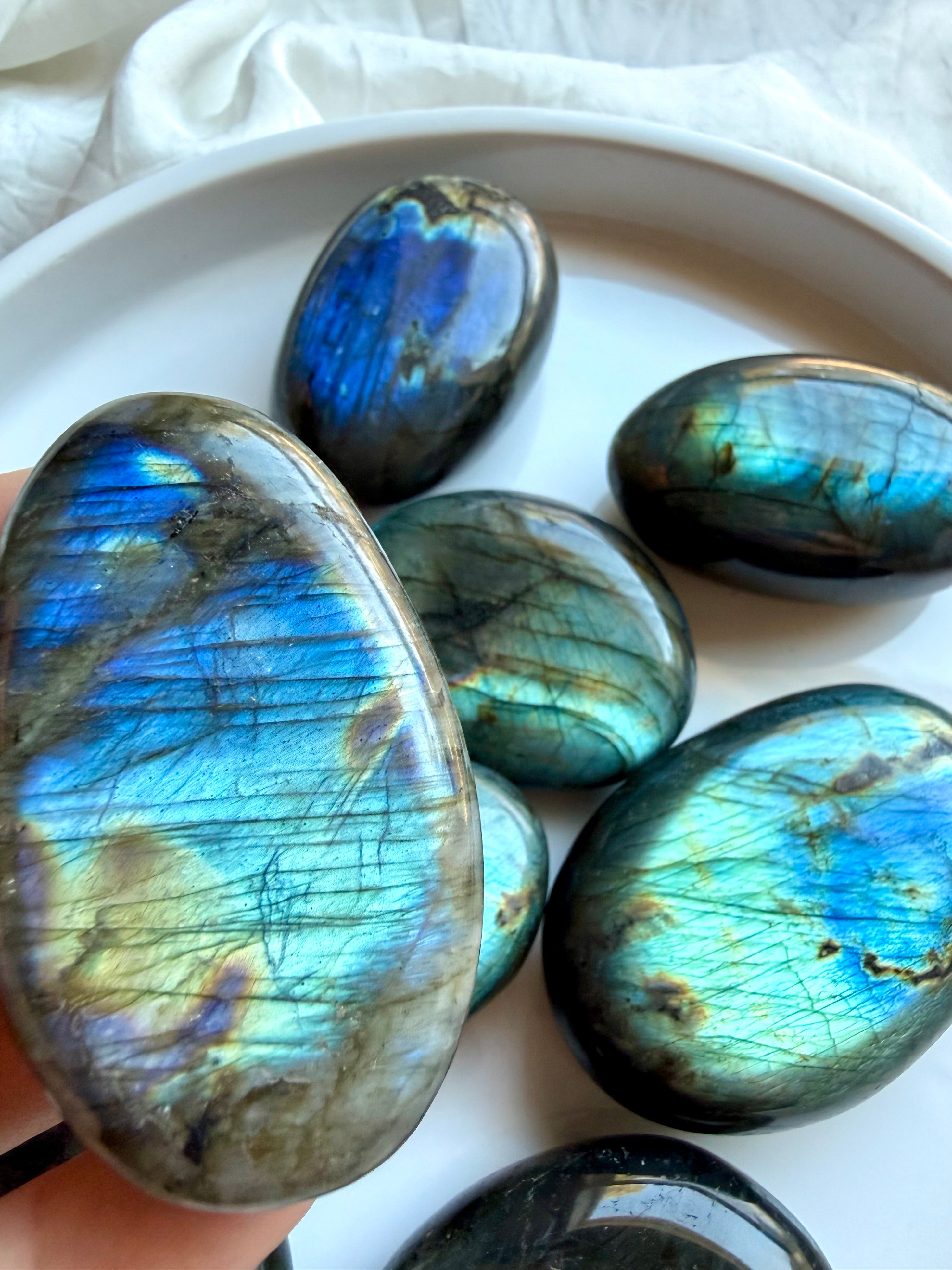 Labradorite palm stones showing blue, teal and green flash with natural variation in color and pattern