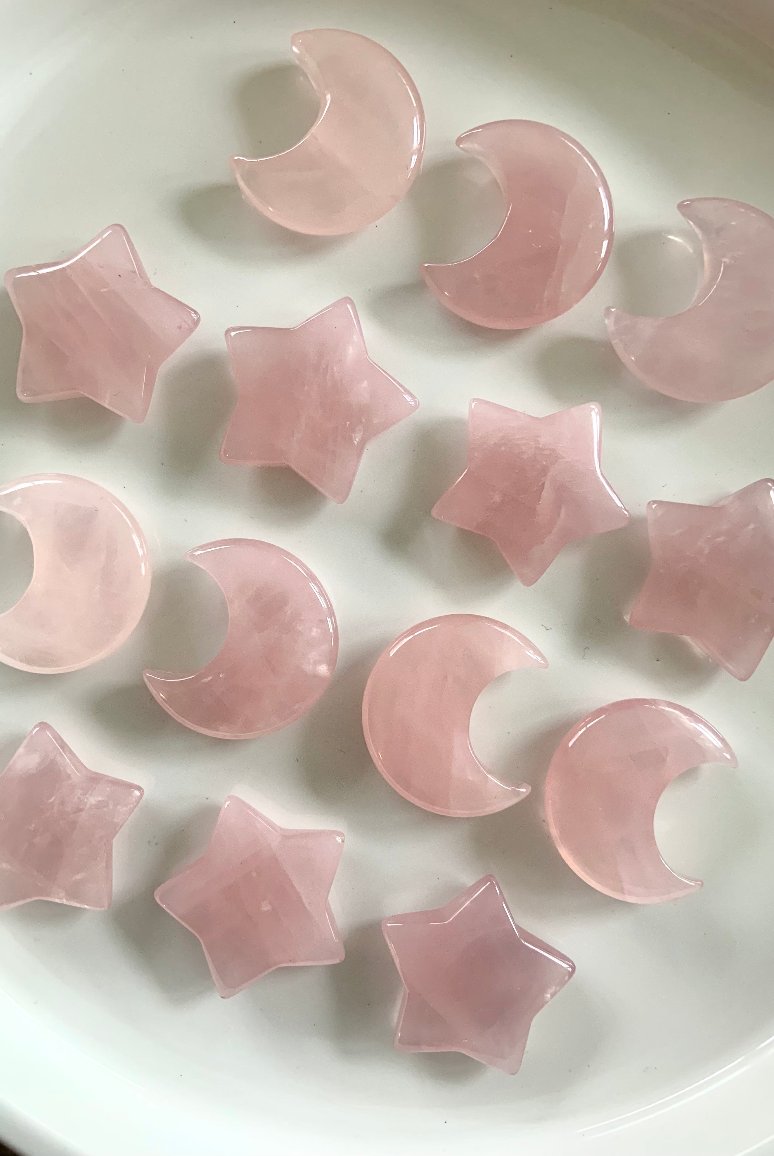 Rose quartz moons and stars in rows on white background