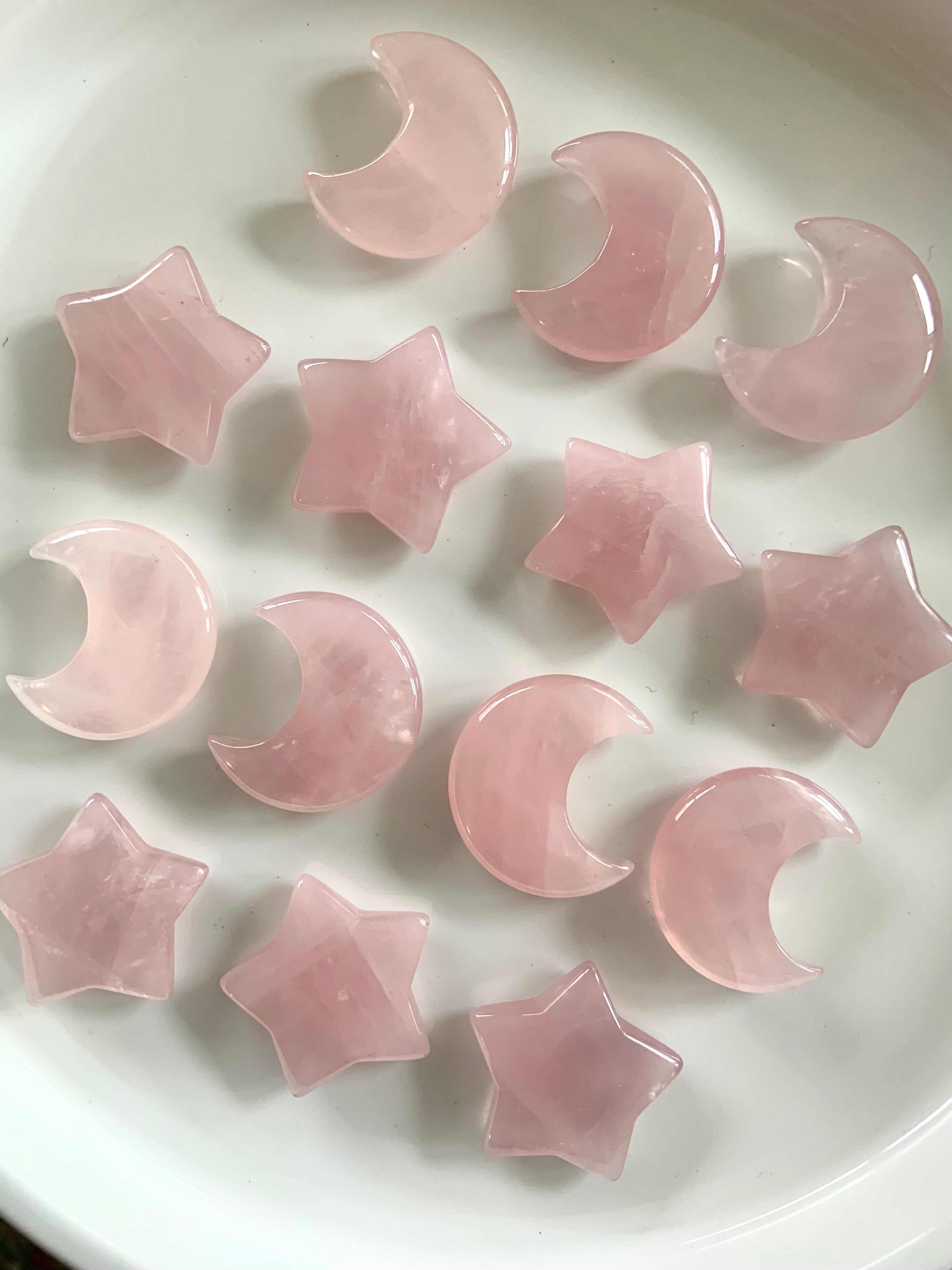 Rose quartz moons and stars in rows on white background