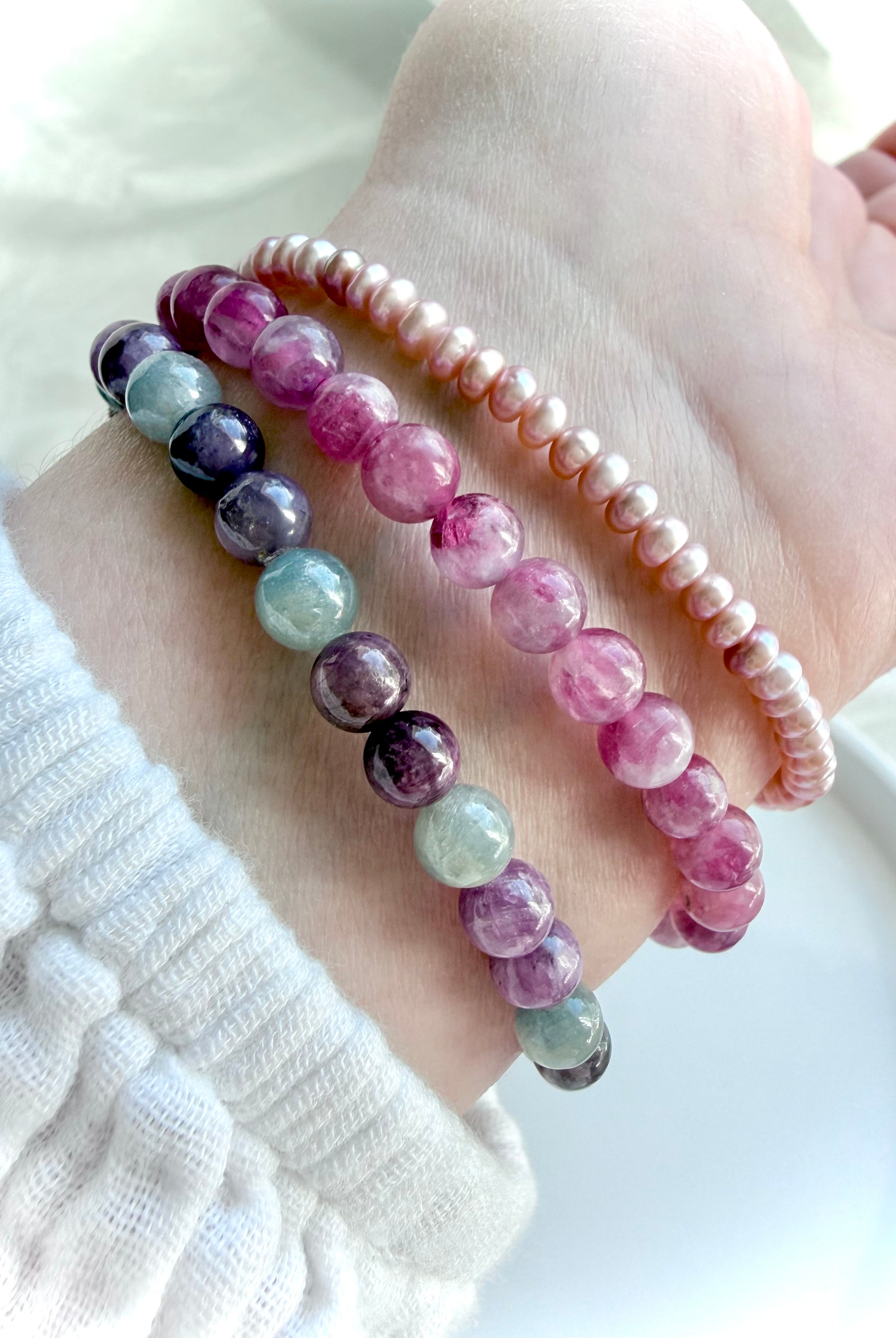 Pink Tourmaline bracelet layered with Ruby Sapphire and Pink Pearl bracelets, highlighting complementary crystal bracelet styling