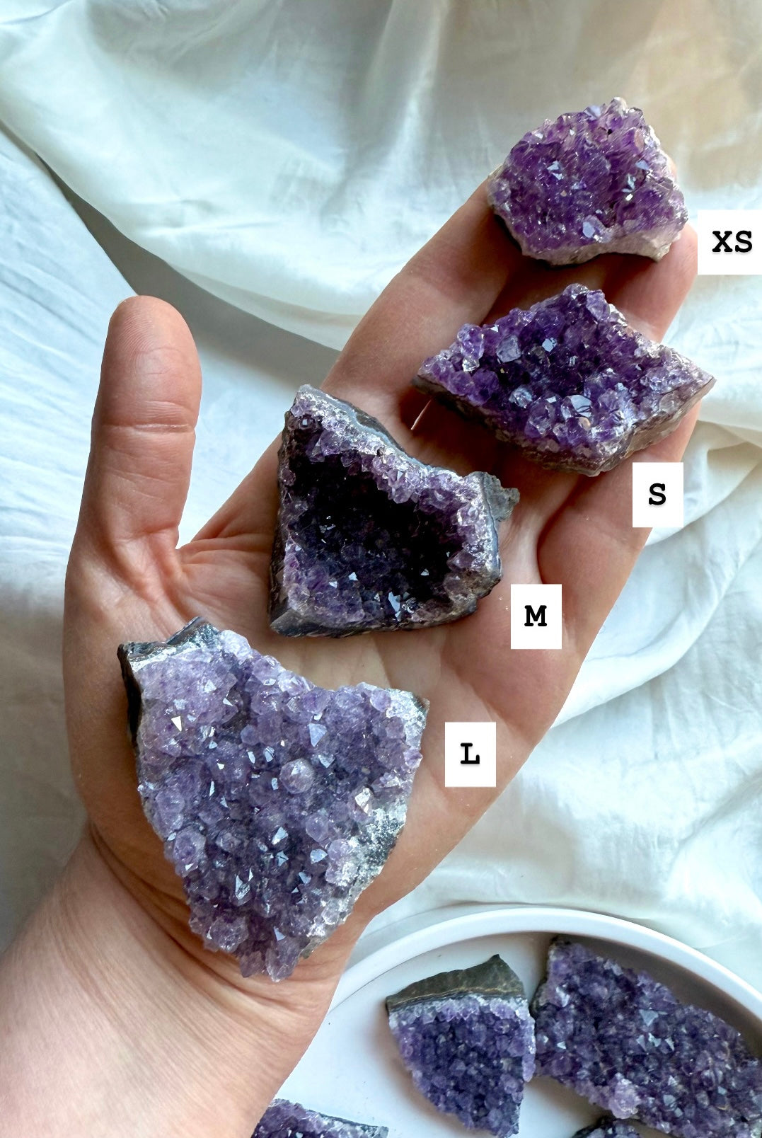 Amethyst crystal clusters XS to Large shown in hand with size labels