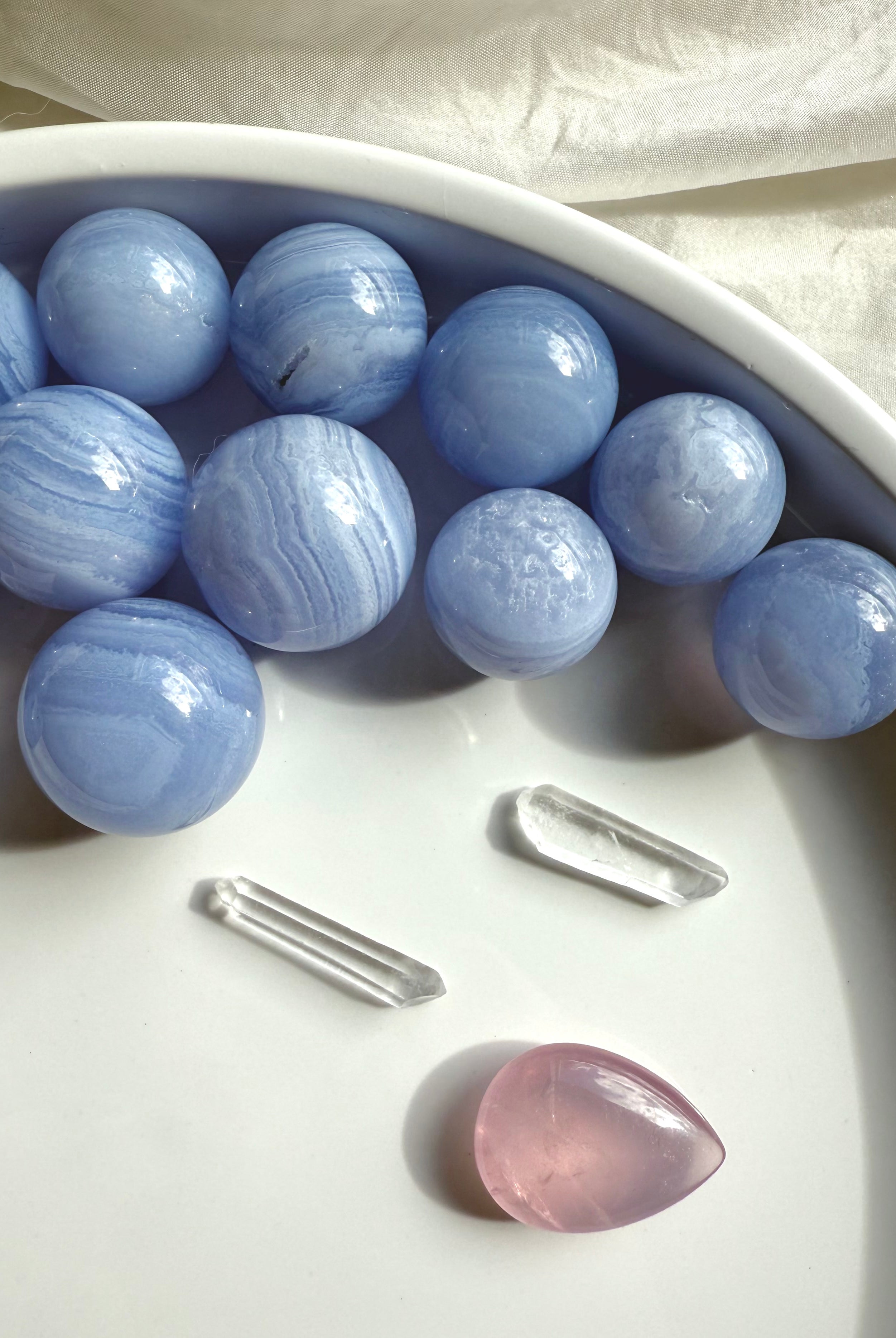 High quality mini Blue Lace Agate Spheres photographed on a white plate in natural light