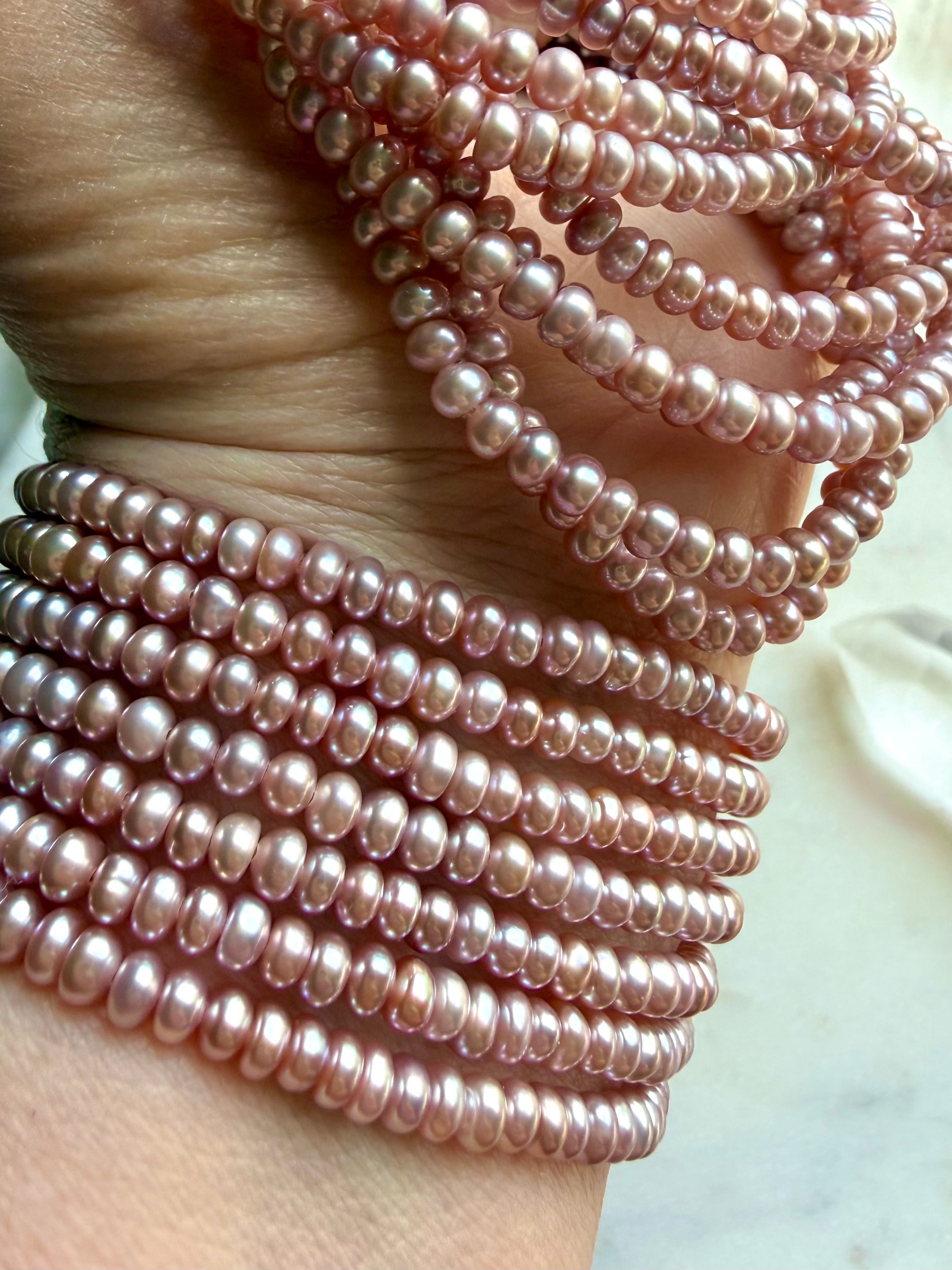 stacked pink freshwater pearl bracelets on wrist, layered pearl jewelry for love, elegance, and heart chakra healing