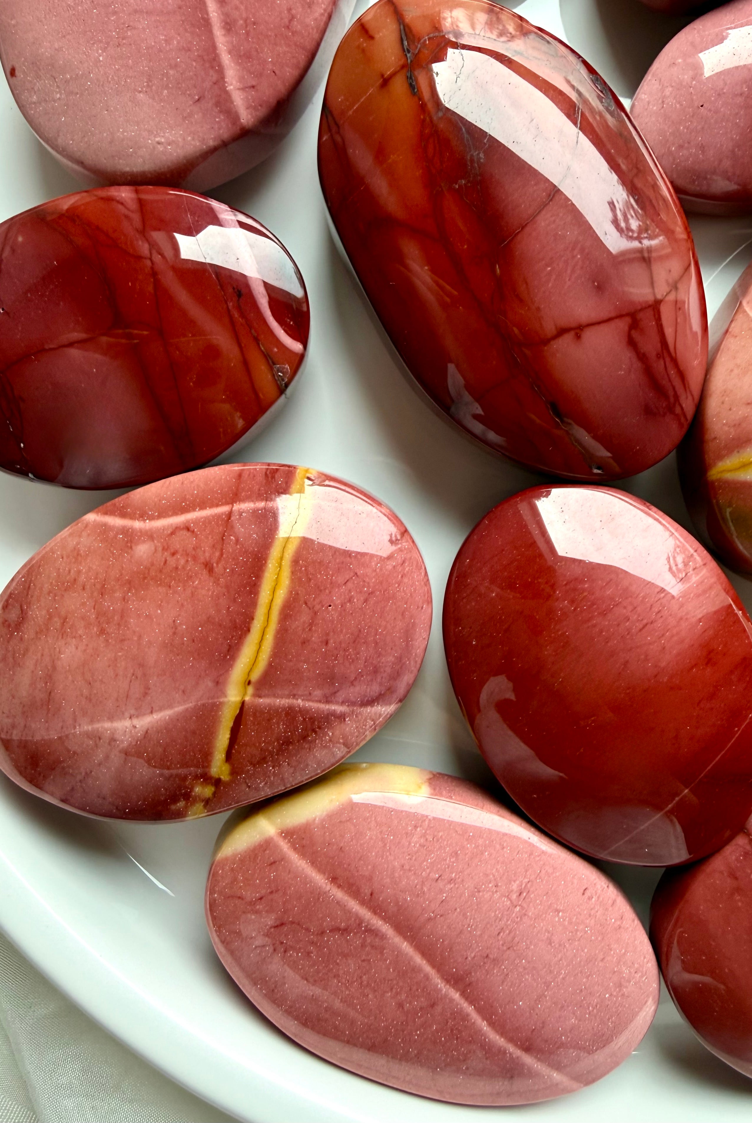 Mookaite Jasper palm stones displayed in ceramic bowl with smooth polished finish and natural earthy color variation