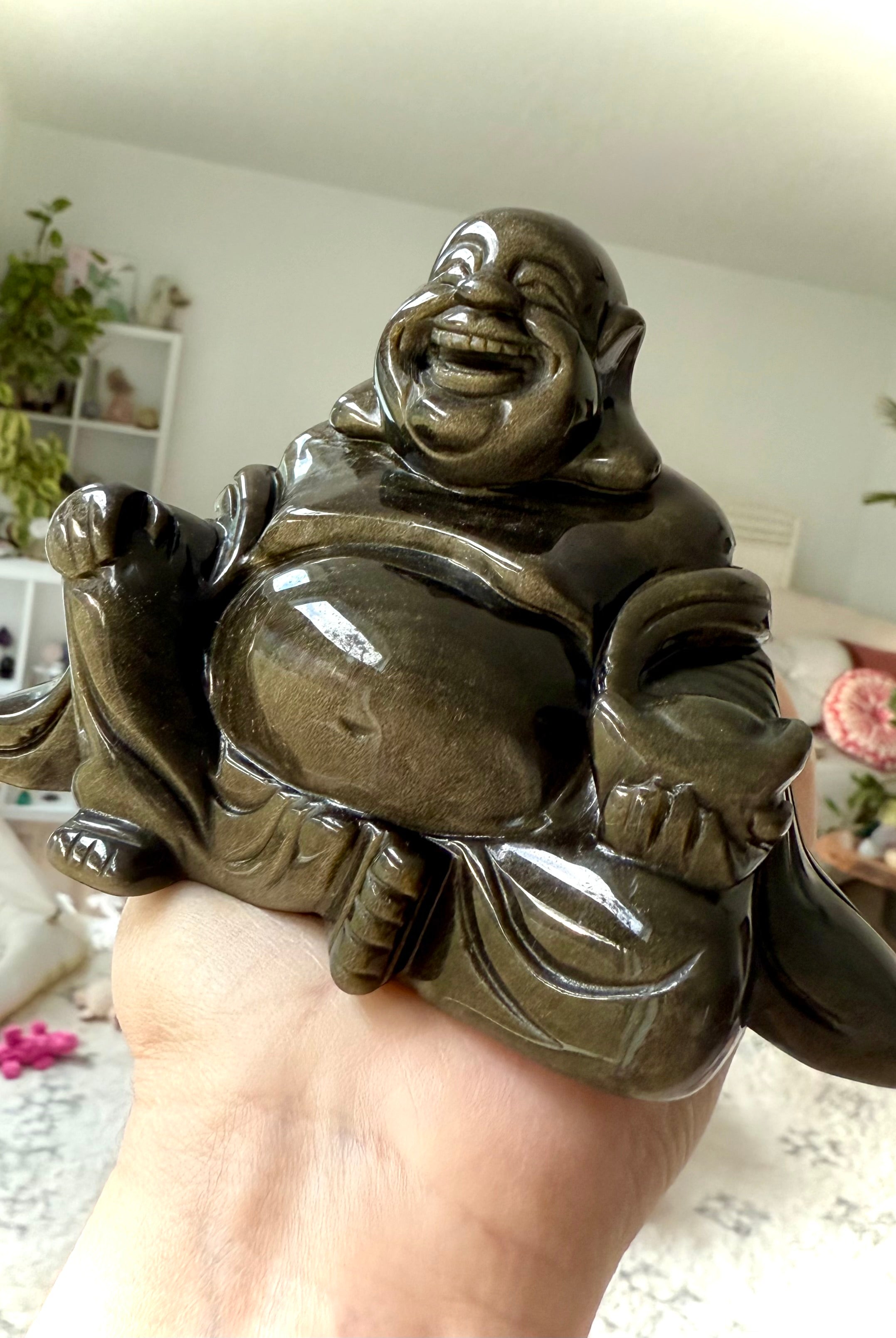 Golden Sheen Obsidian Buddha carving in hand, showing gold flash and joyful energy, healing crystal statue for luck and happiness