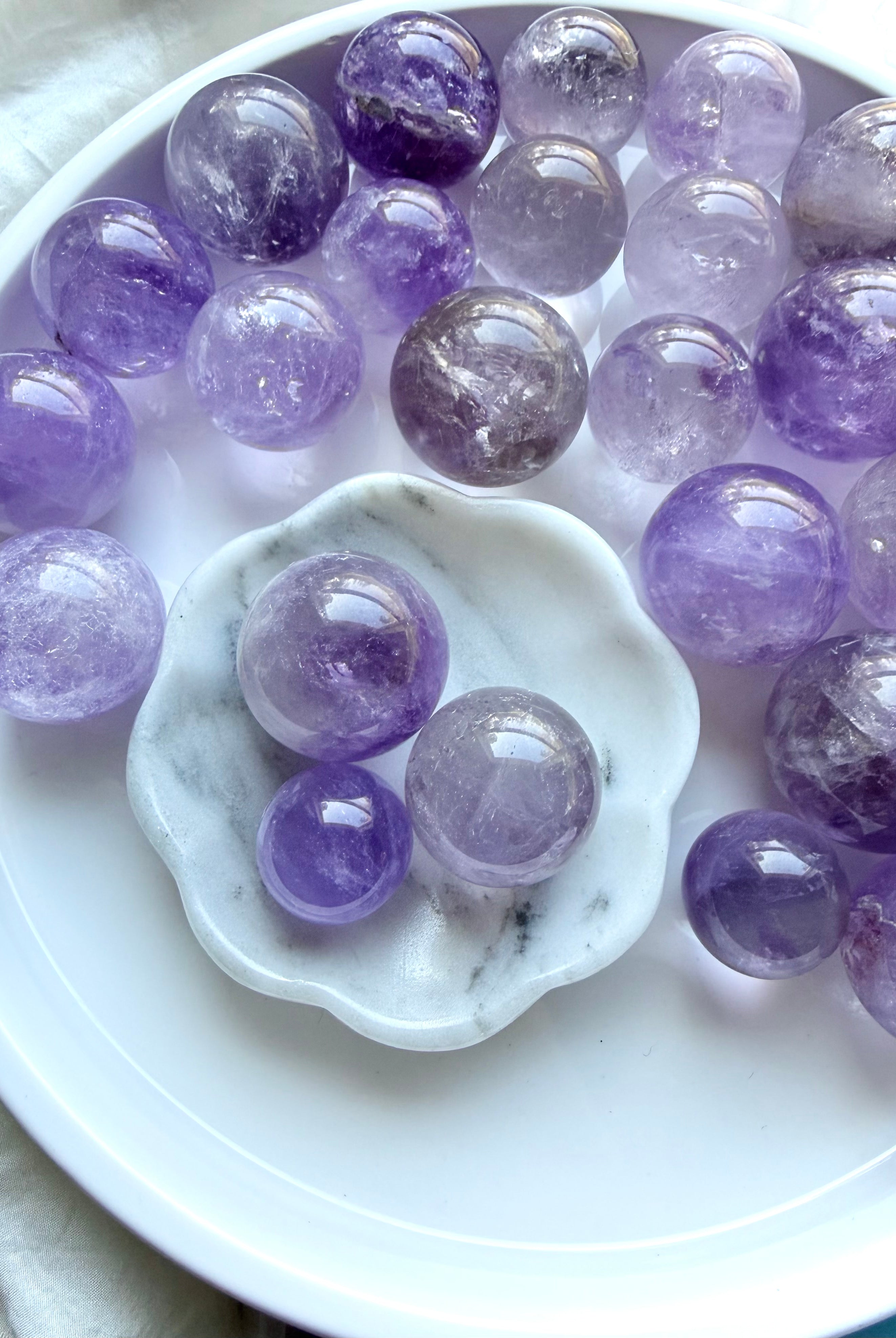 smoky amethyst mini spheres arranged on white tray with marble dish small crystal balls in soft purple tones