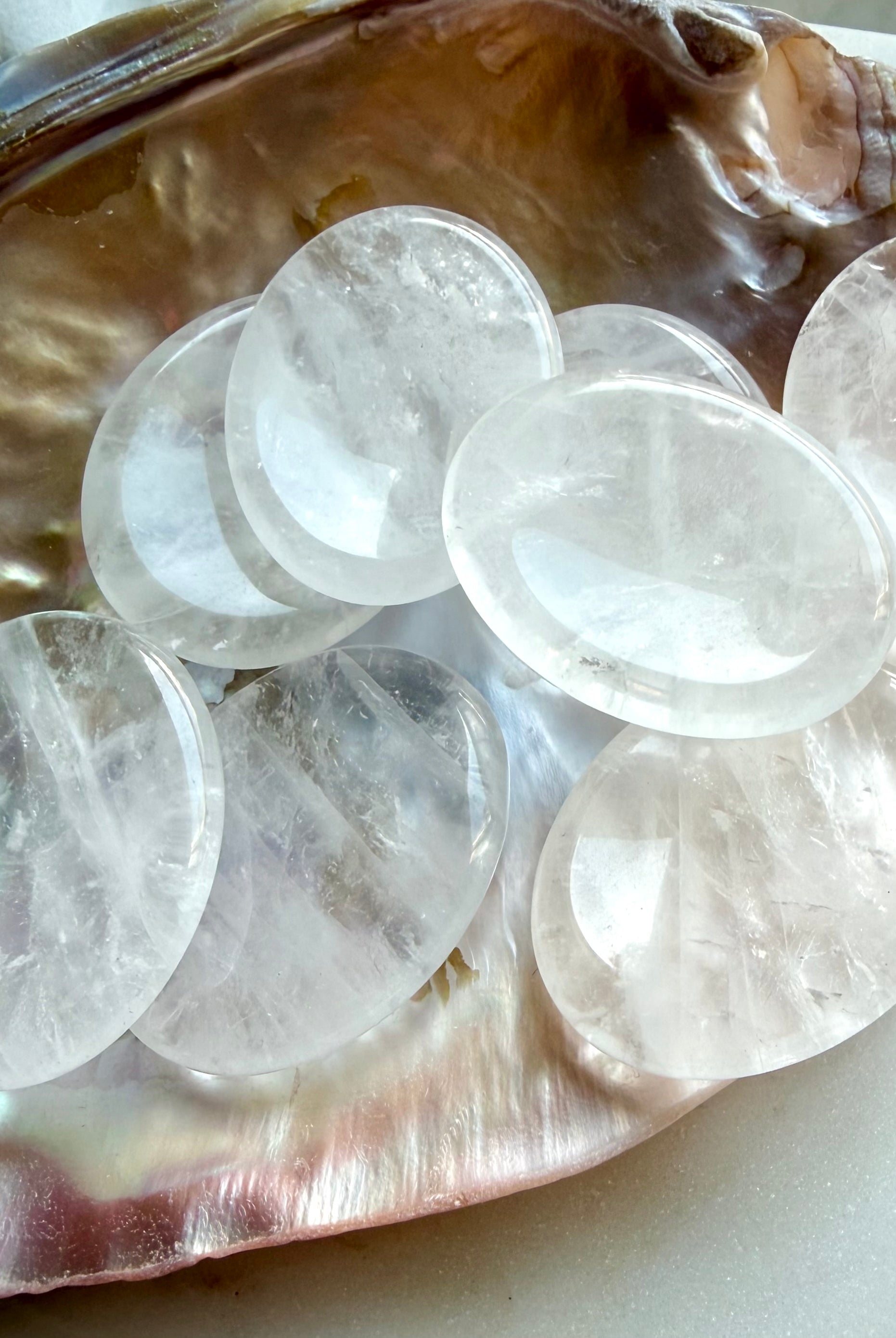 clear quartz worry stones grouped on shell dish for meditation clarity and energy amplification