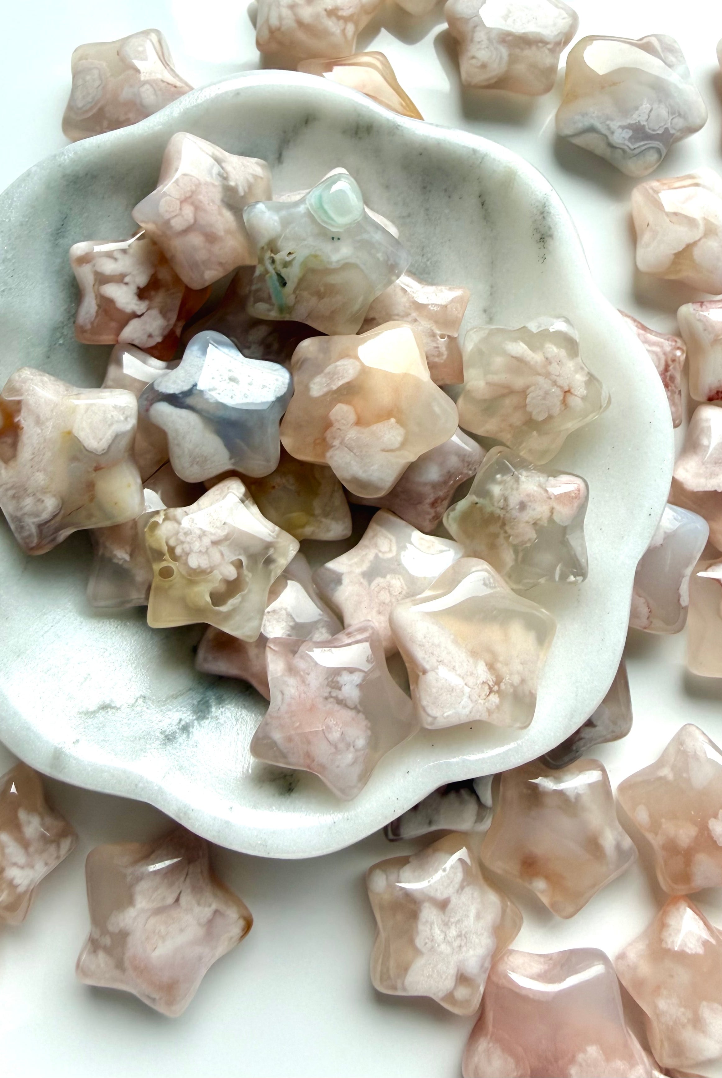 Mini Flower Agate star carvings in soft pink and cream tones displayed in a marble bowl