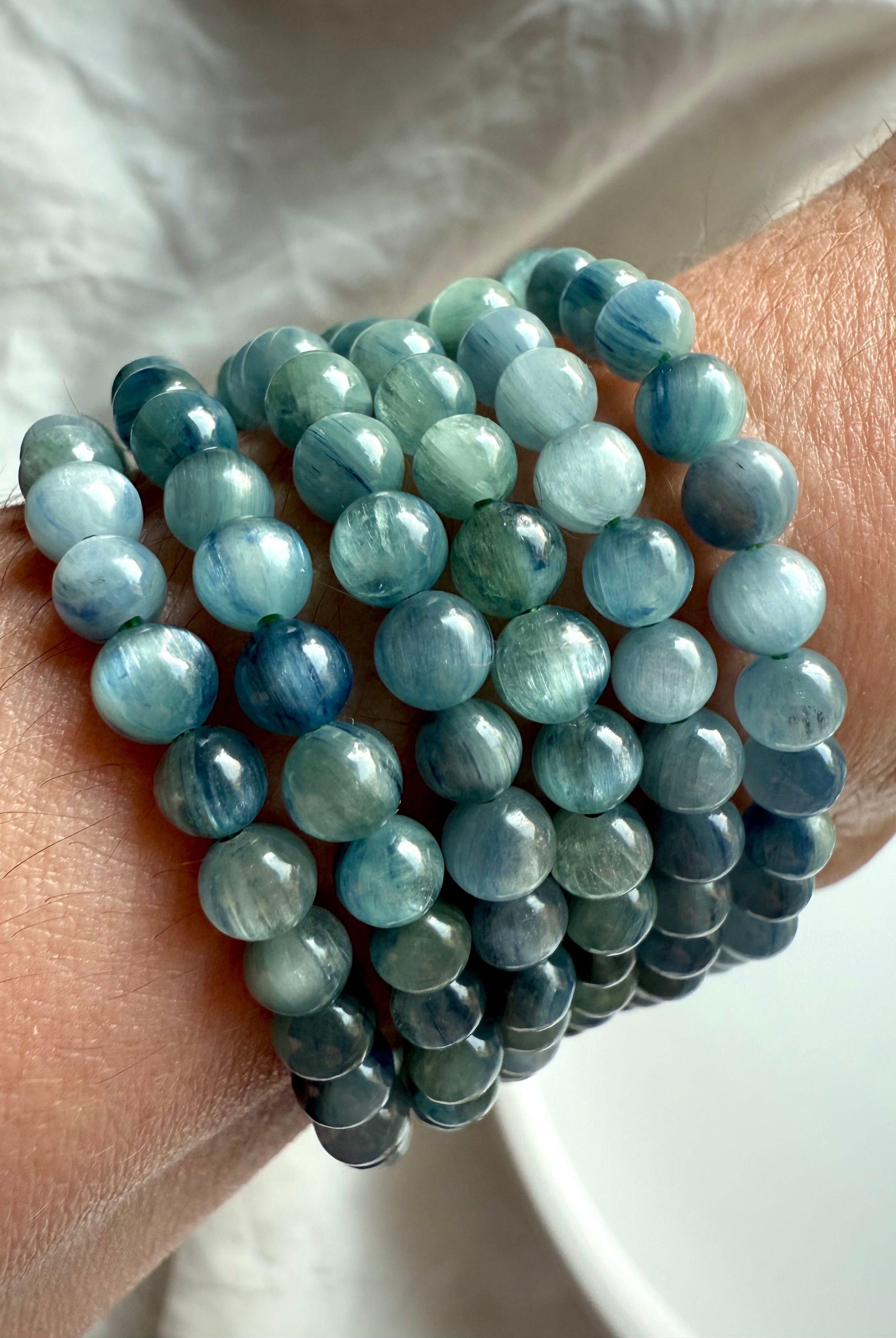 side view of blue-green kyanite bracelets on wrist highlighting the soft glow and metaphysical energy of this throat chakra stone