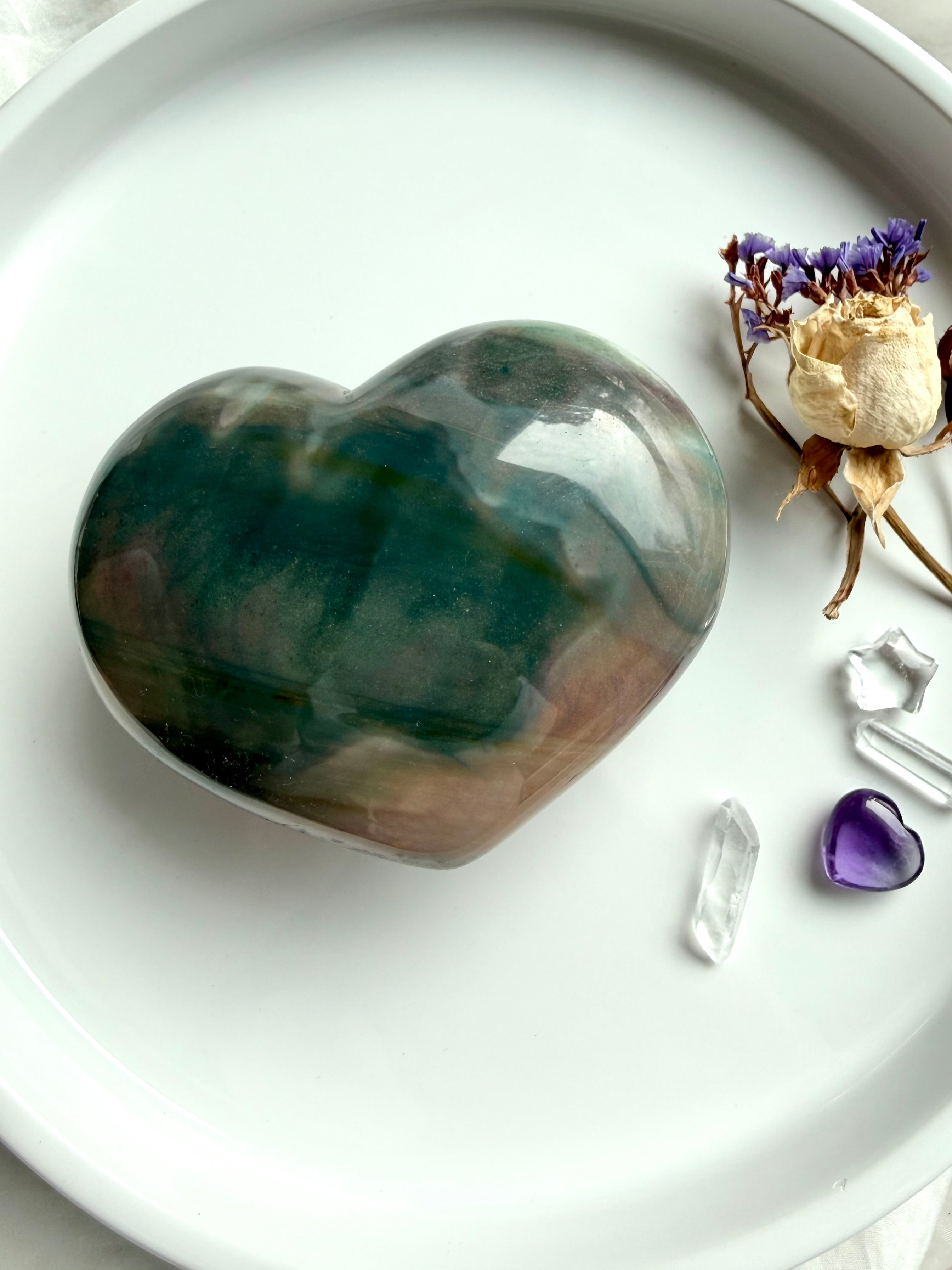 Ocean Jasper heart beside crystals and flowers for size reference with polished pastel tones