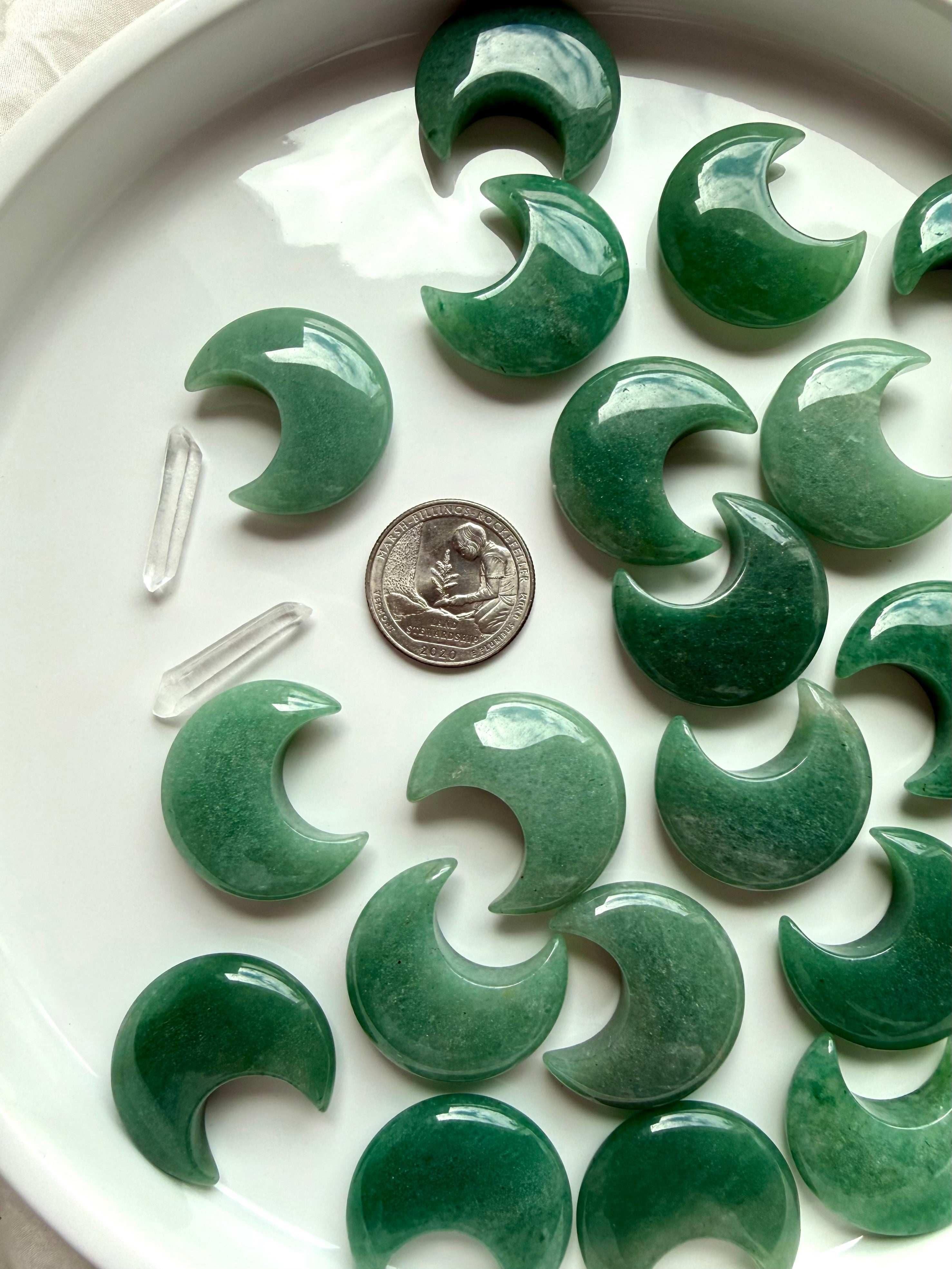 Flatlay of Green Aventurine moons on white plate with quarter for scale, crystal carvings for altar décor and meditation
