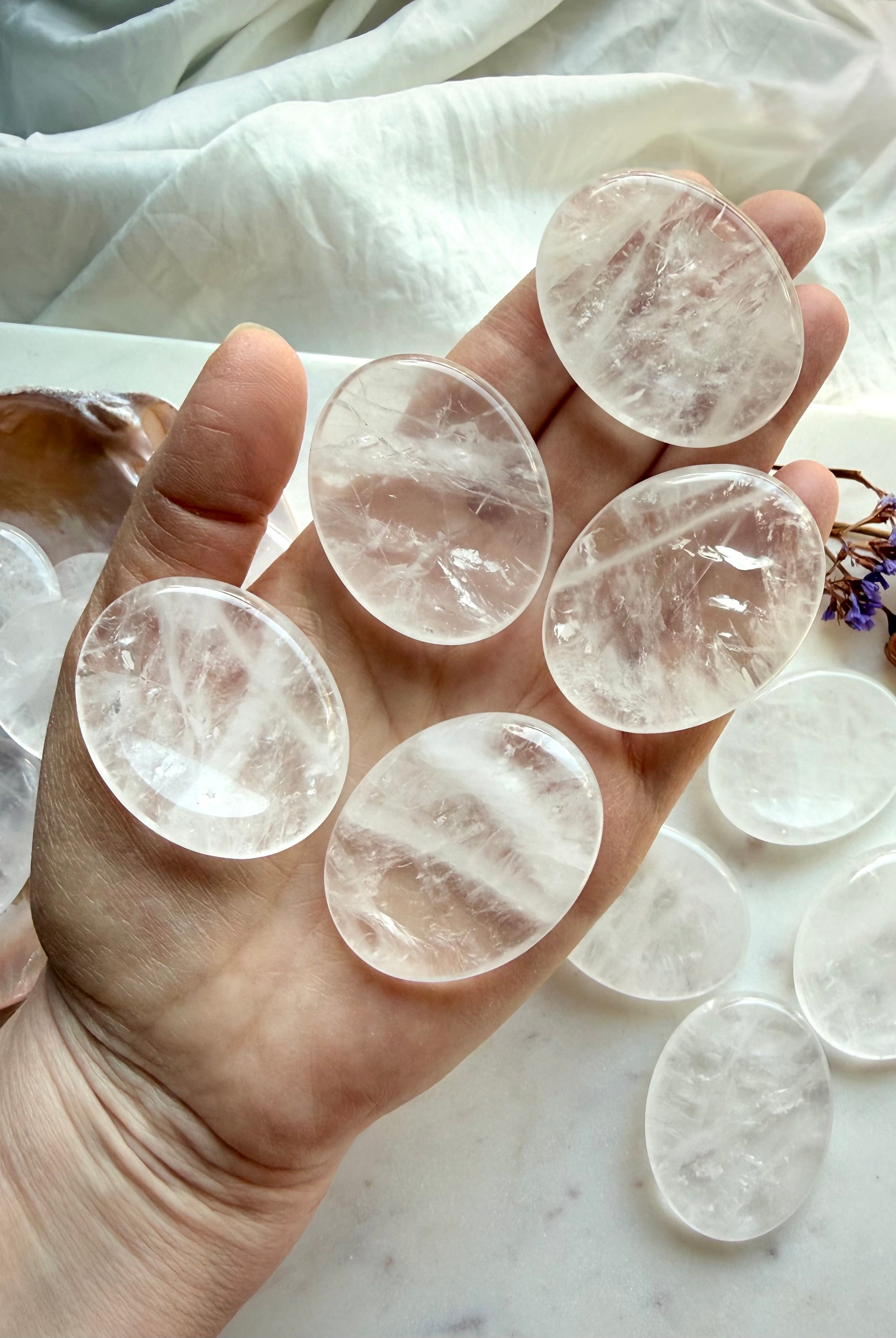 several clear quartz thumb stones in hand for focus clarity and calming energy support