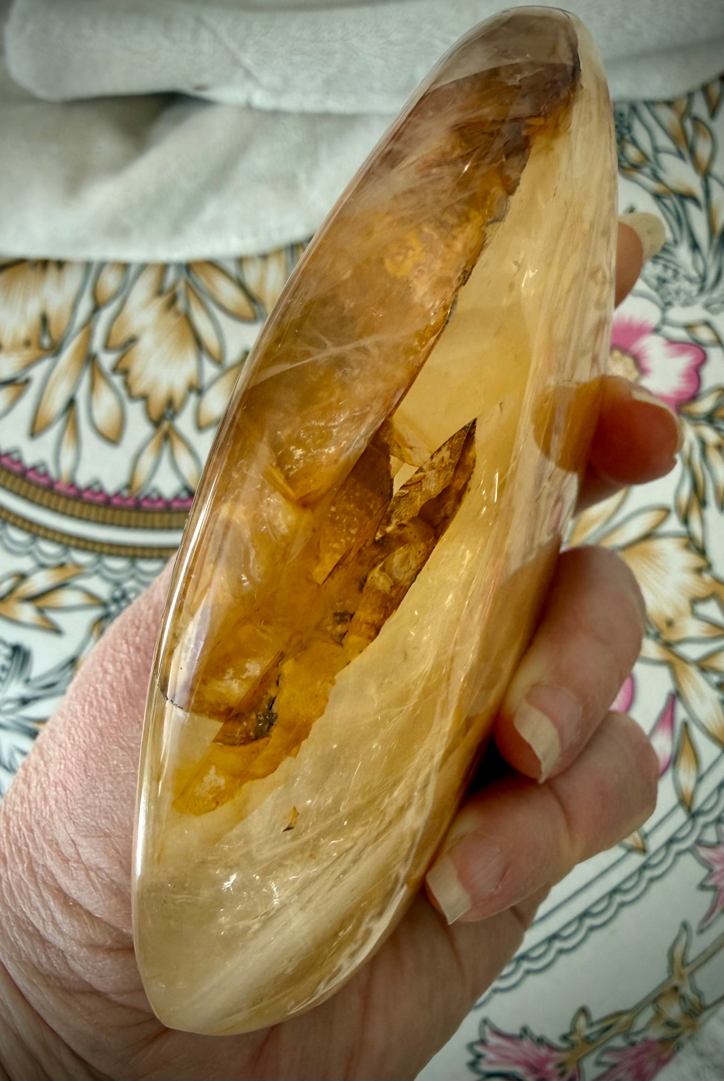 Side view of polished Golden Healer Quartz display crystal with luminous amber-gold tones and sculptural form
