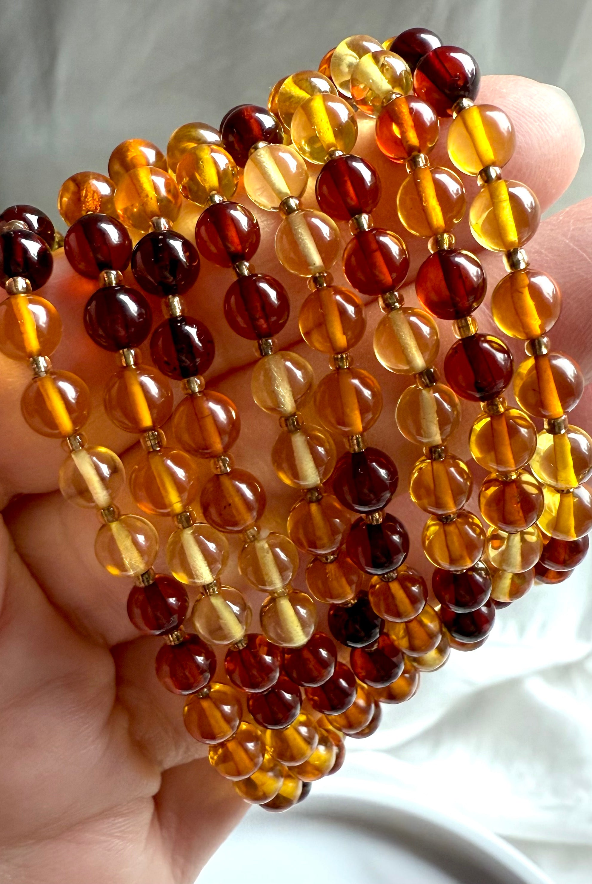 Close-up of multi-tone amber bracelets in sunshine yellow, golden honey + deep cognac – Solar Plexus crystal healing jewelry
