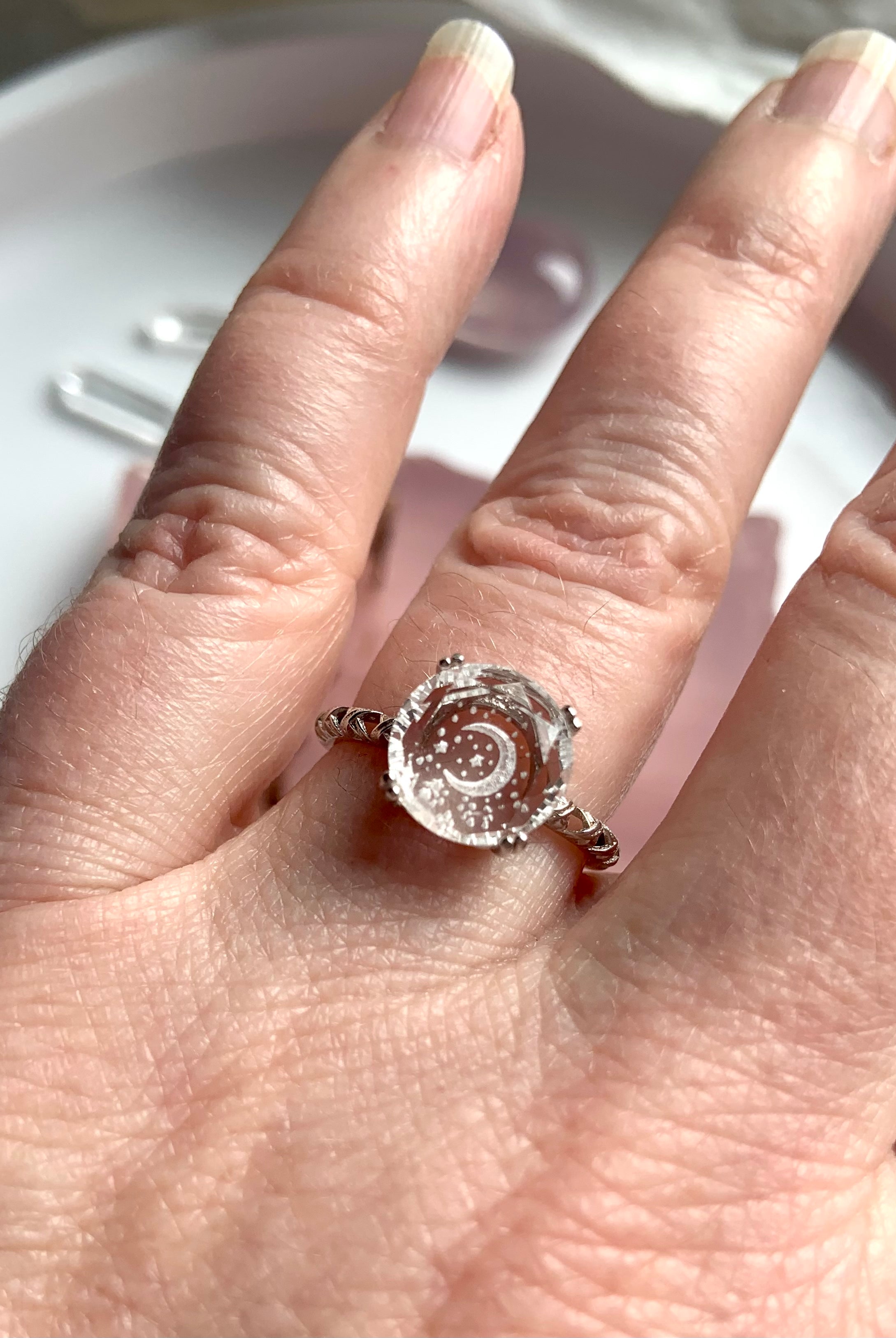 hand wearing clear quartz moon ring with detailed silver band