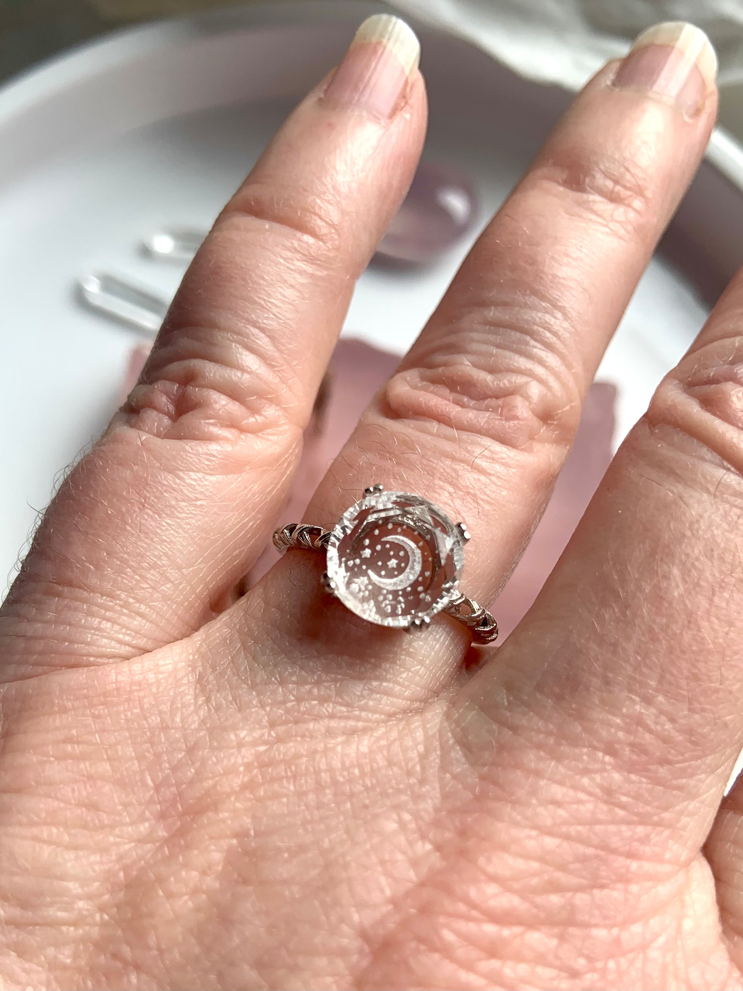 hand wearing clear quartz moon ring with detailed silver band