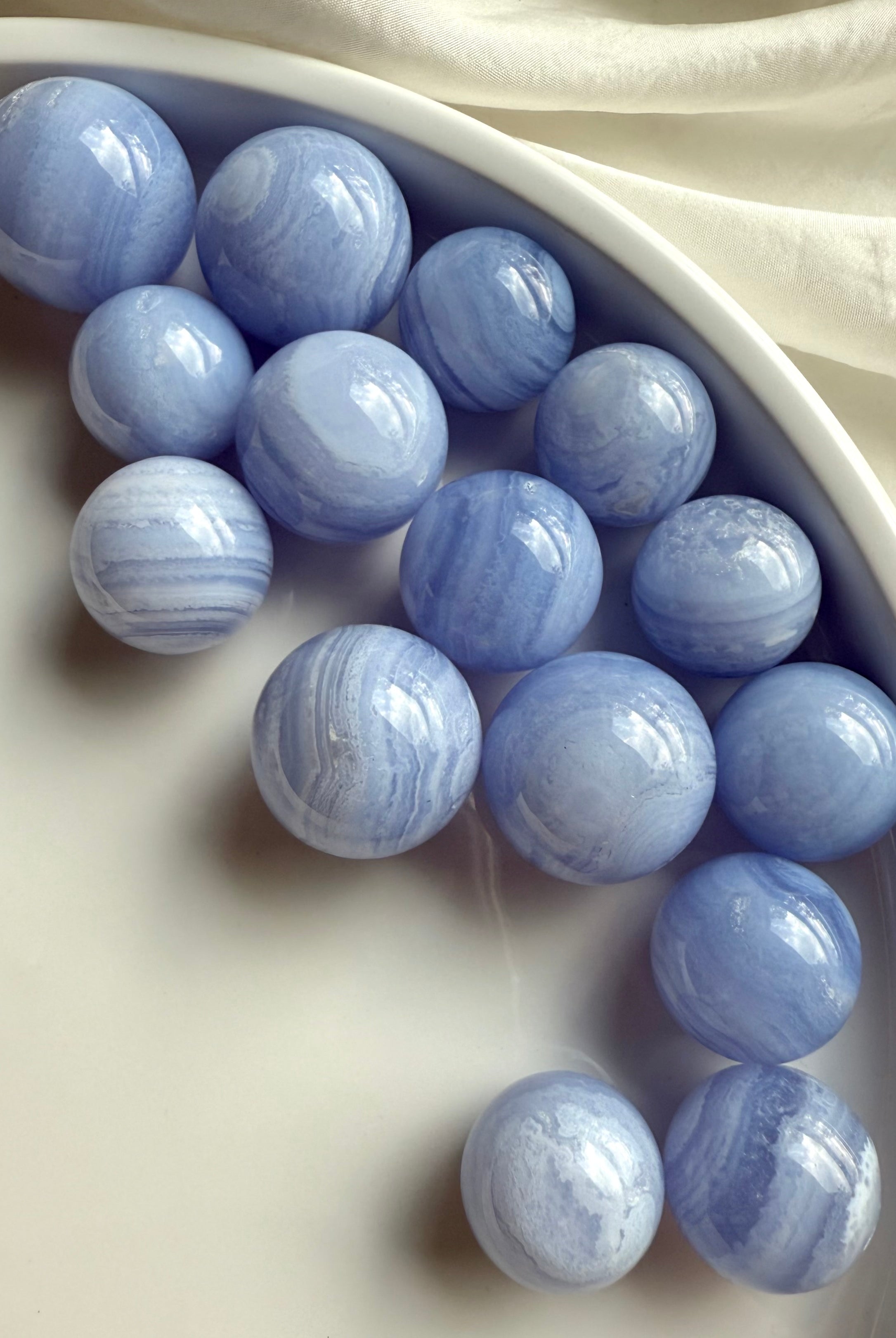 An array of mini sized high quality Blue Lace Agate Spheres on a white plate