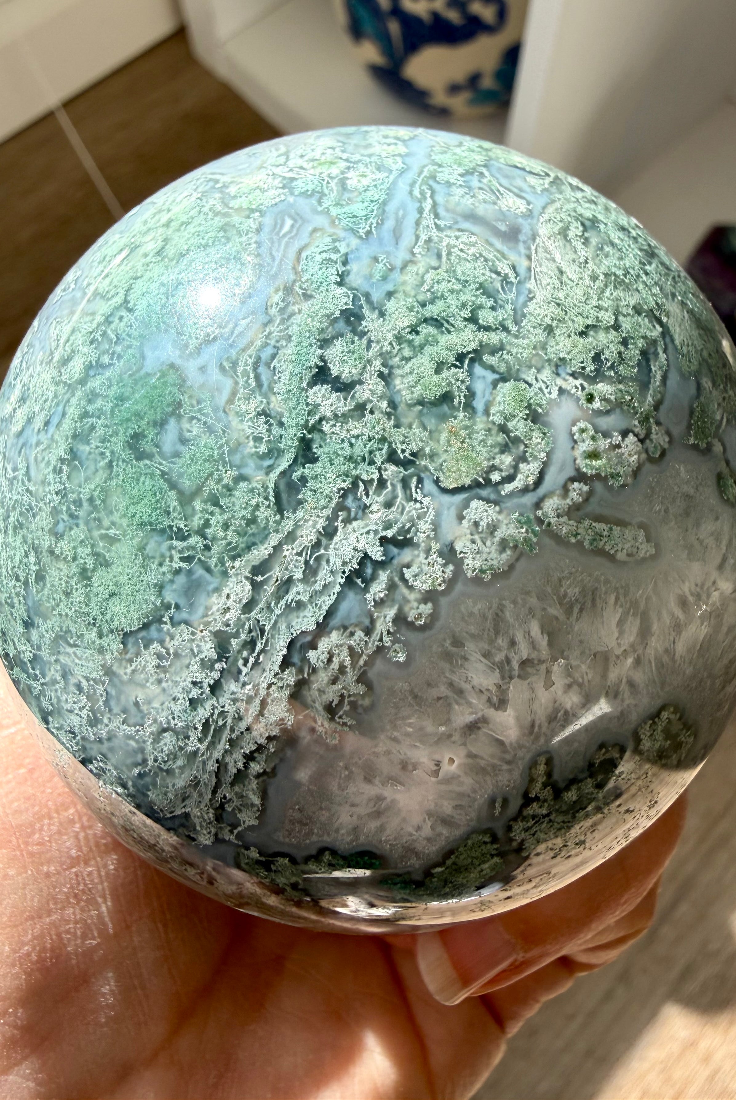 Moss Agate sphere close up showing detailed green moss patterns, Quartz pockets, and polished finish