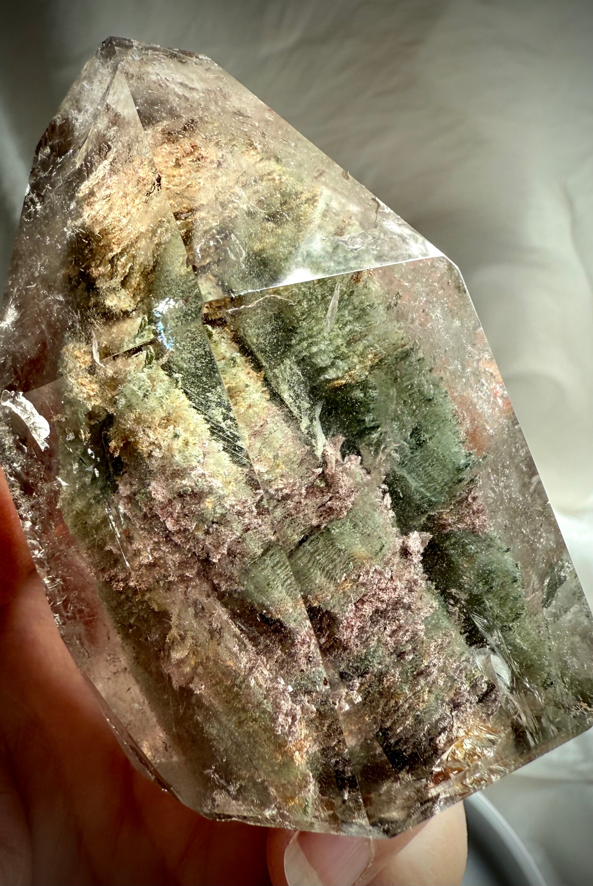 Thousand Layer Garden Quartz phantom crystal held in hand showing size, clarity, and layered chlorite inclusions