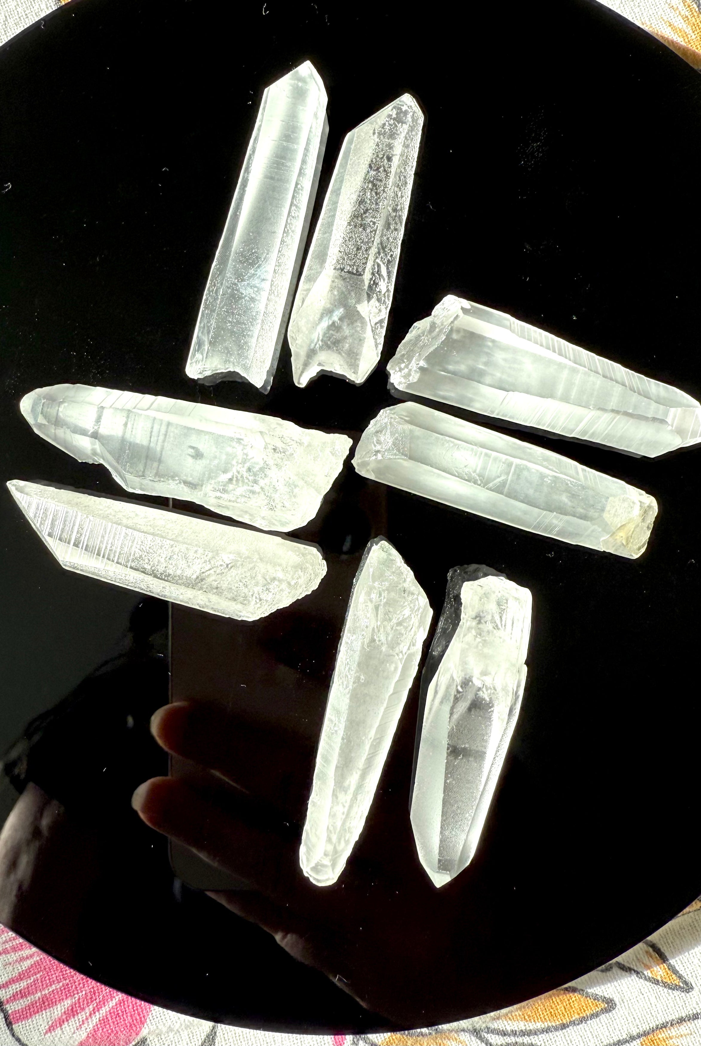 High-vibe Lemurian Quartz points laid out in a geometric grid on an obsidian plate — used for grounding, clarity & ascension work