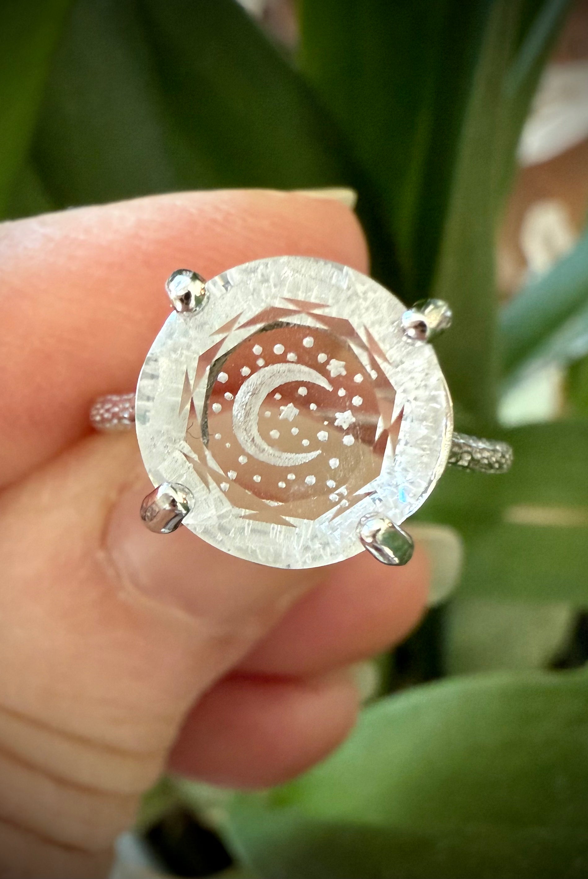 Close-up of Clear Quartz Crescent Moon Ring worn on finger with faceted gem and celestial etching set in sterling silver