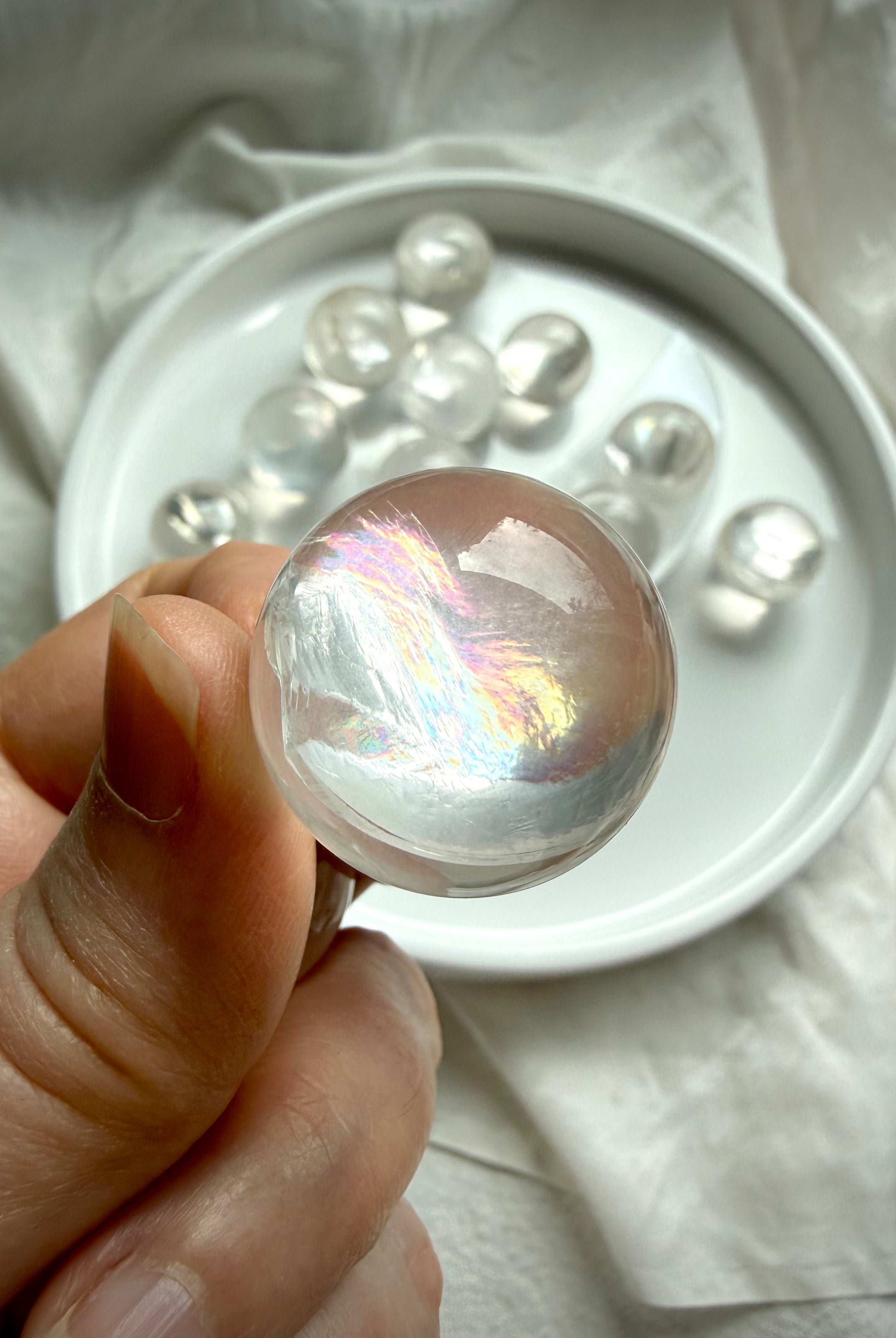 Close-up of rainbow girasol mini quartz sphere with opaline milky translucency and subtle internal rainbow flash