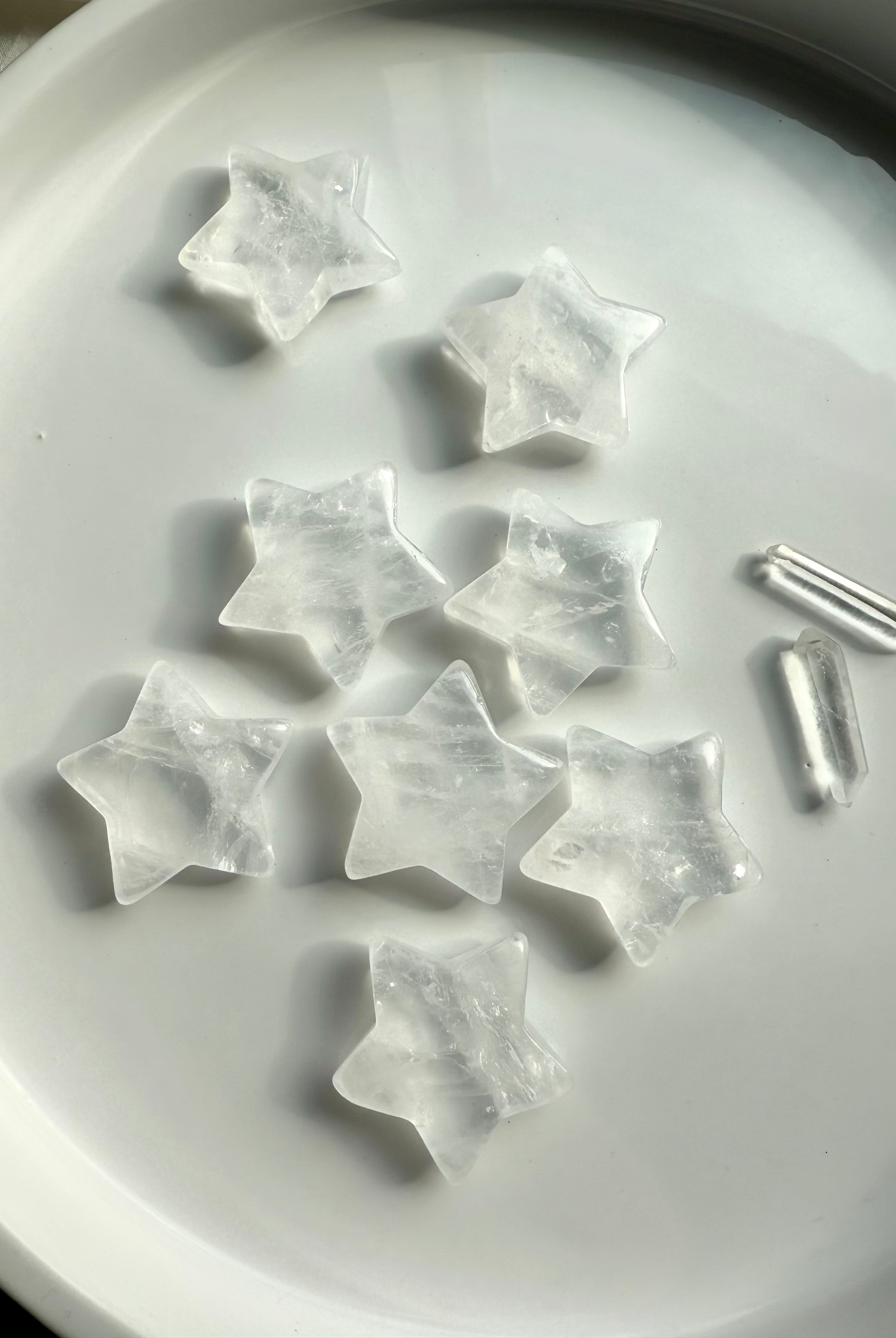 Array of Clear Quartz star carvings on a white plate with quartz points, healing crystals for chakra balance, meditation, and altar décor
