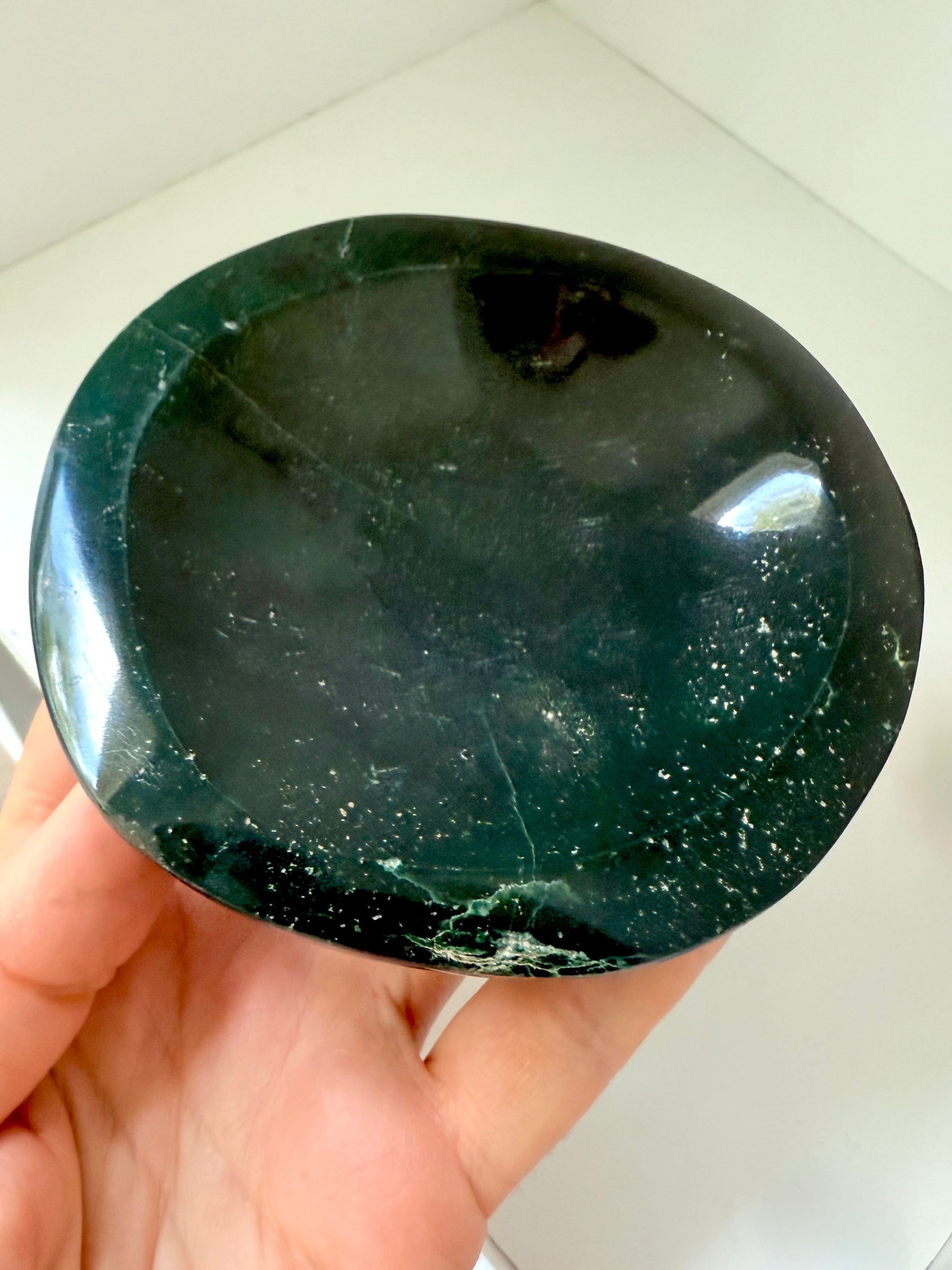 A hand carved teal green Ocean Jasper Bowl held in a hand for scale. Display your treasures in style